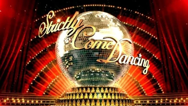 Logo for 'Strictly Come Dancing' with a large disco ball, red curtains, and stage lighting.