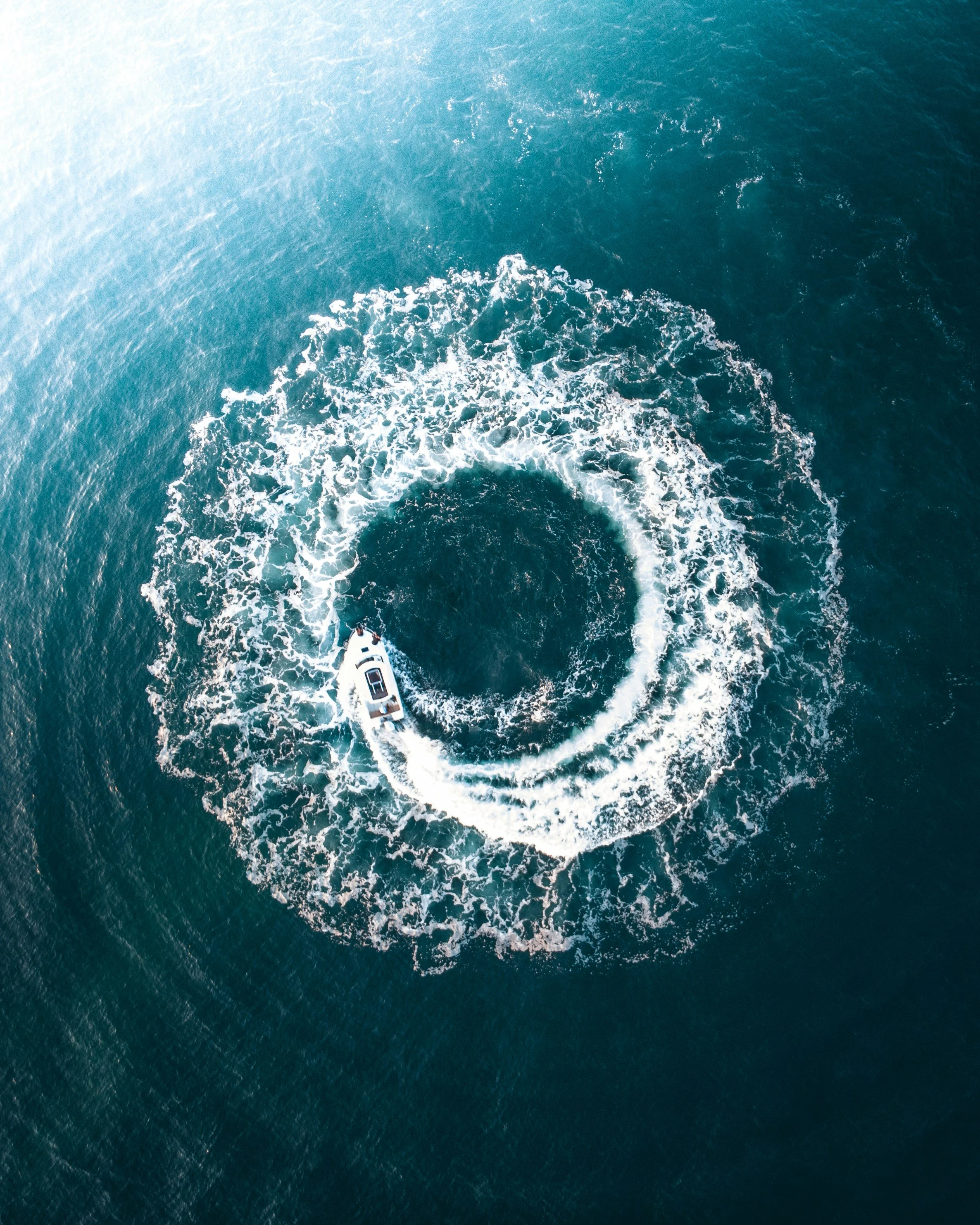 Aerial view of a boat creating a circle in the ocean