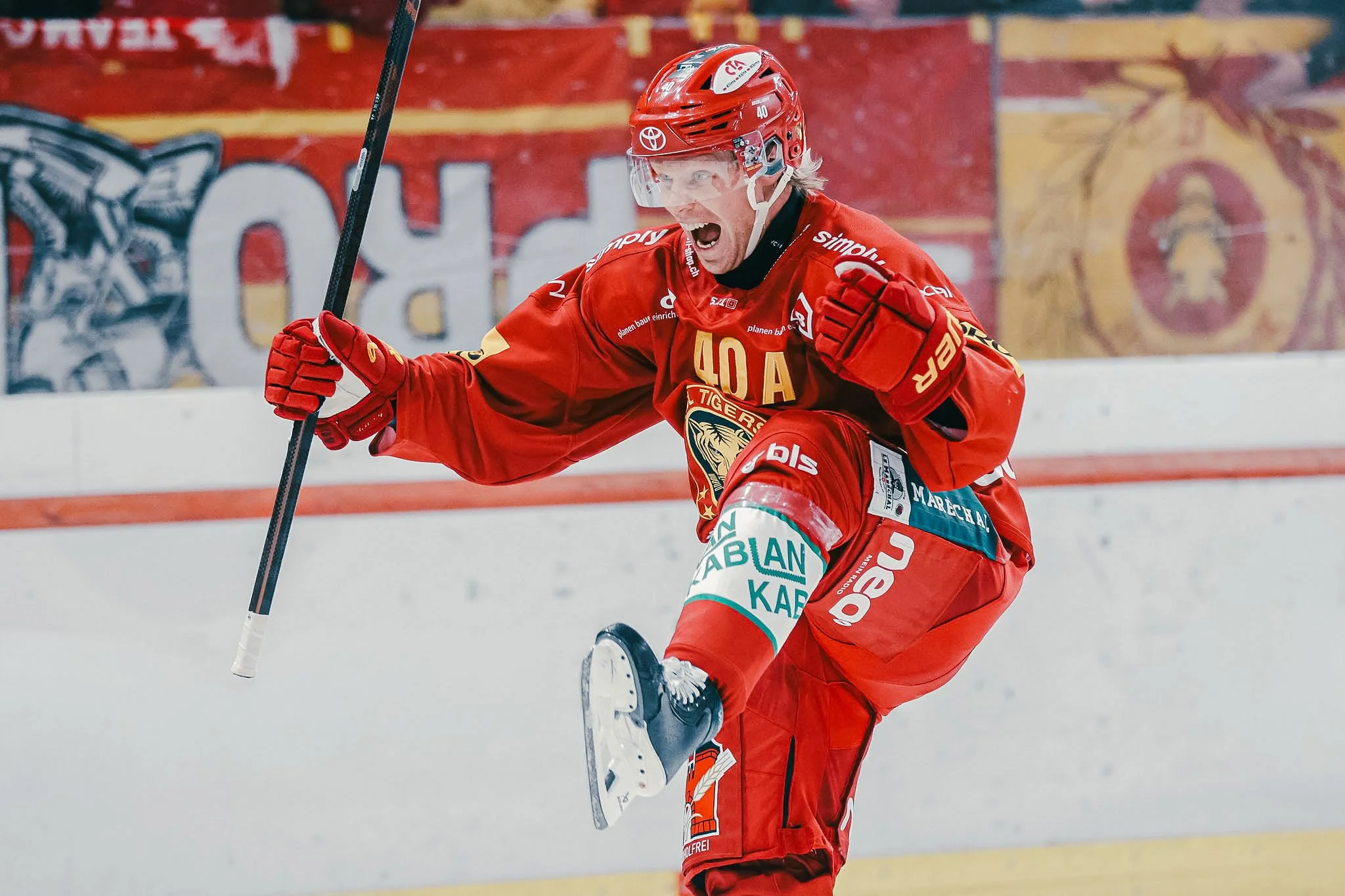 Eishockeyspieler in rotem Trikot jubelt auf dem Eis