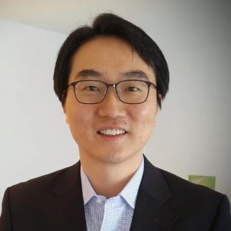 A man with glasses, short black hair, wearing a dark suit and light shirt, smiling in front of a plain background. Member of the AI Aptitude Institute Advisory Board and expert in enterprise AI strategy,