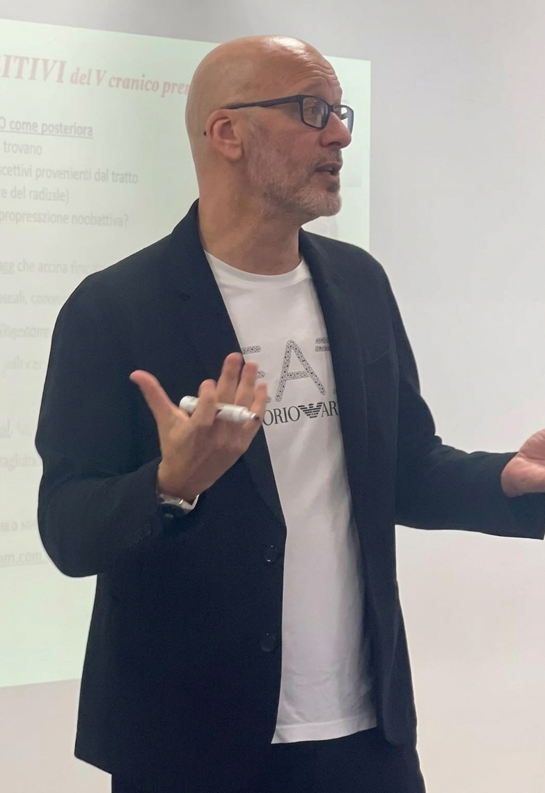 Uomo che tiene un pennarello e parla durante una presentazione, con proiettore sullo sfondo.