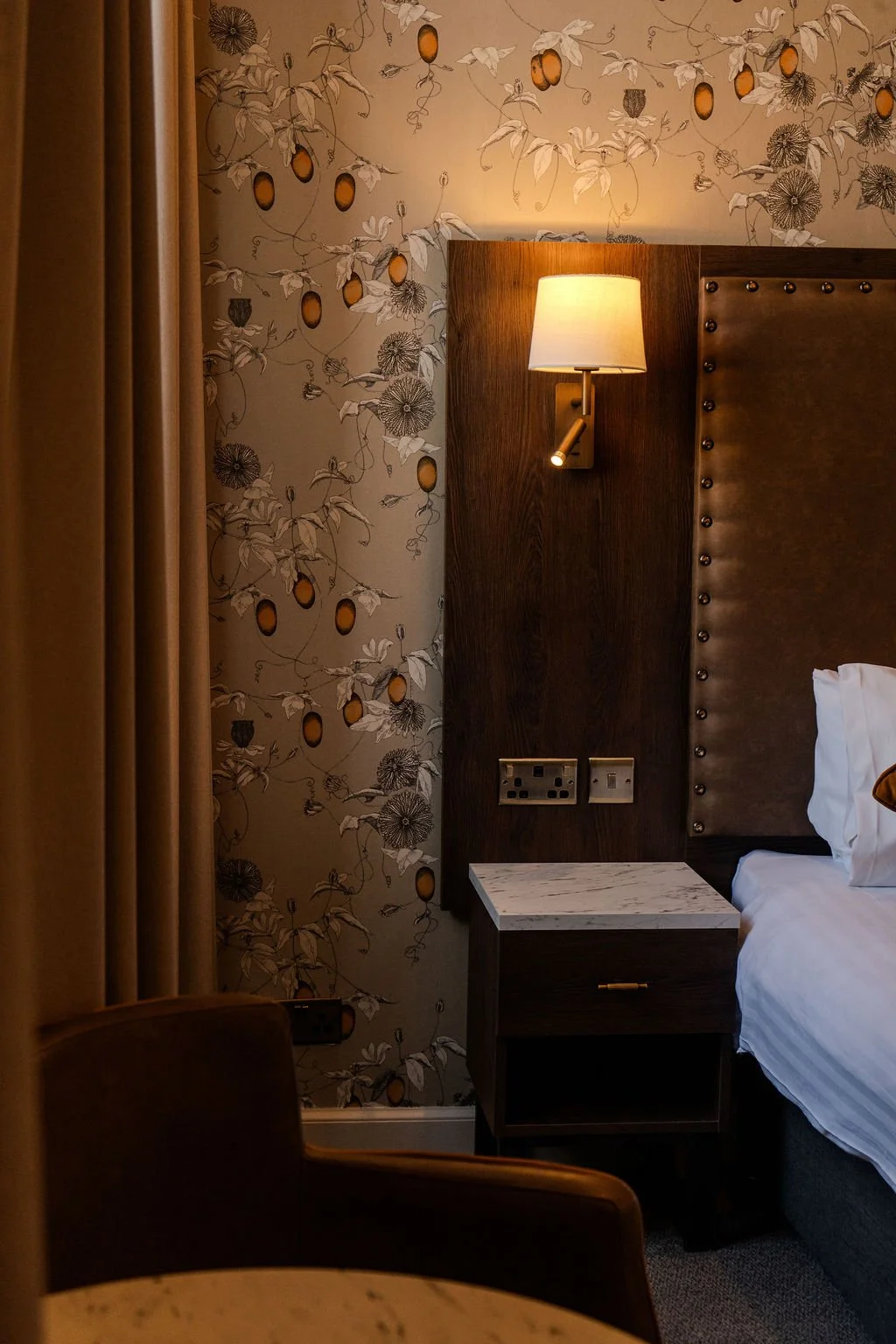A neatly made bed with white pillows and bed linens, viewed through a small opening suggesting a peephole or a narrow frame.