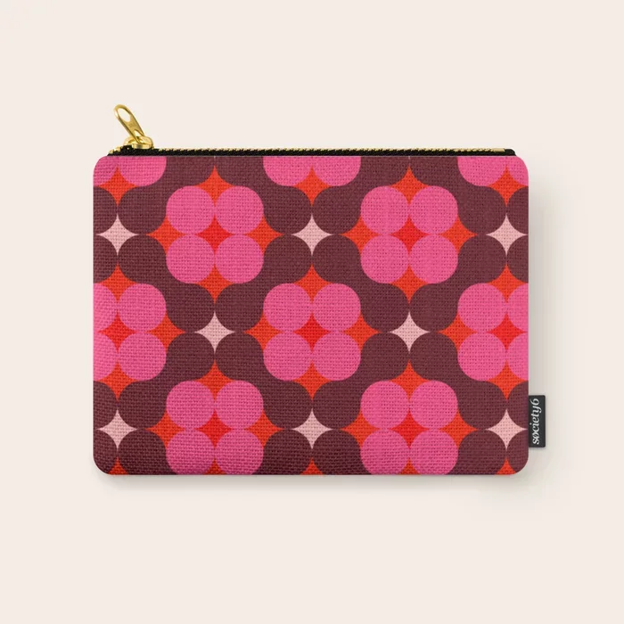 Society6 – The kiss art print. A small fabric pouch with a colourful geometric pattern of pink, purple, red, and white circles and star shapes, with a black zipper at the top and a small black tag on the right side.