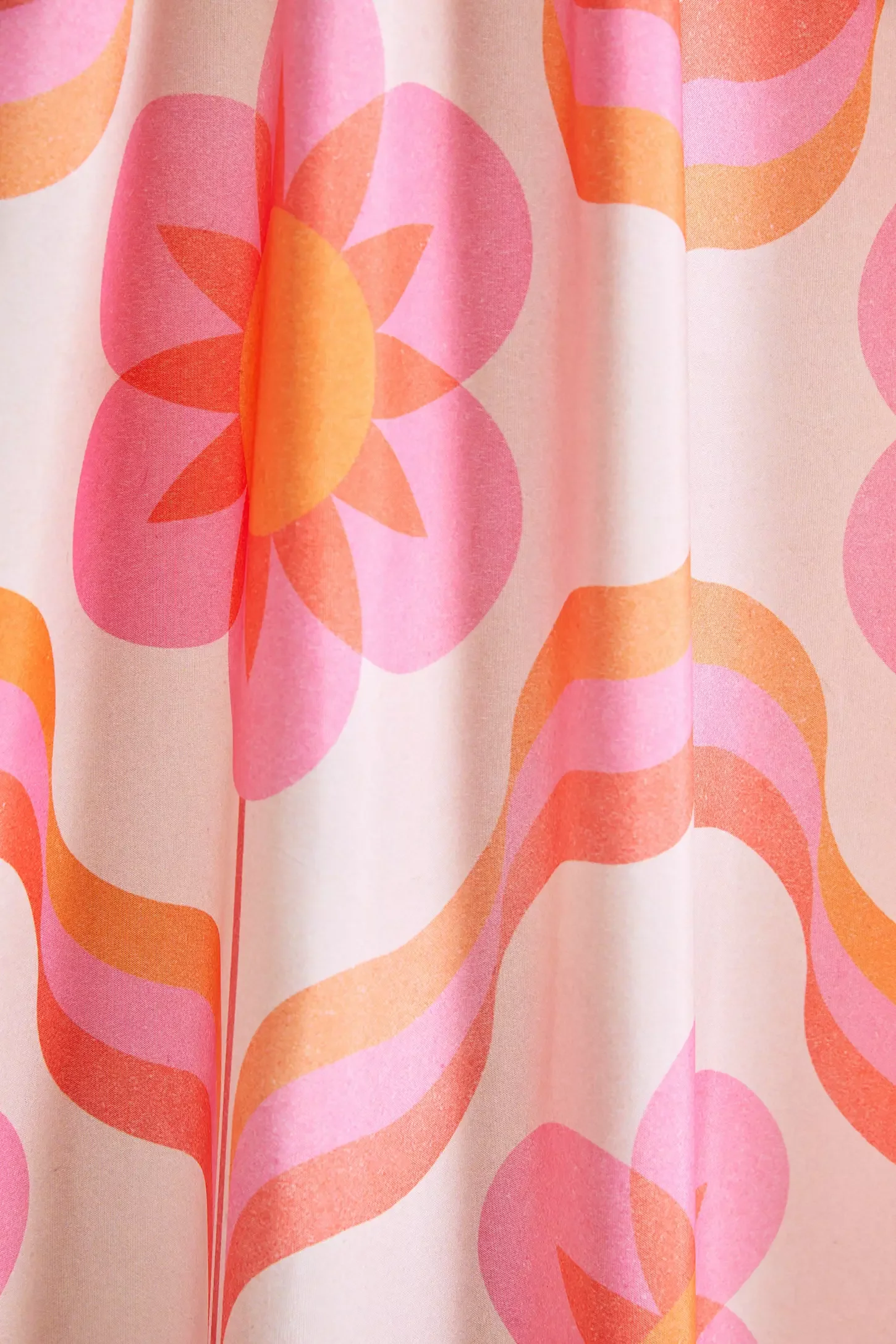 Close-up of a fabric with a colorful, floral pattern featuring pink and orange hues. The fabric appears to be part of a curtain or similar item.