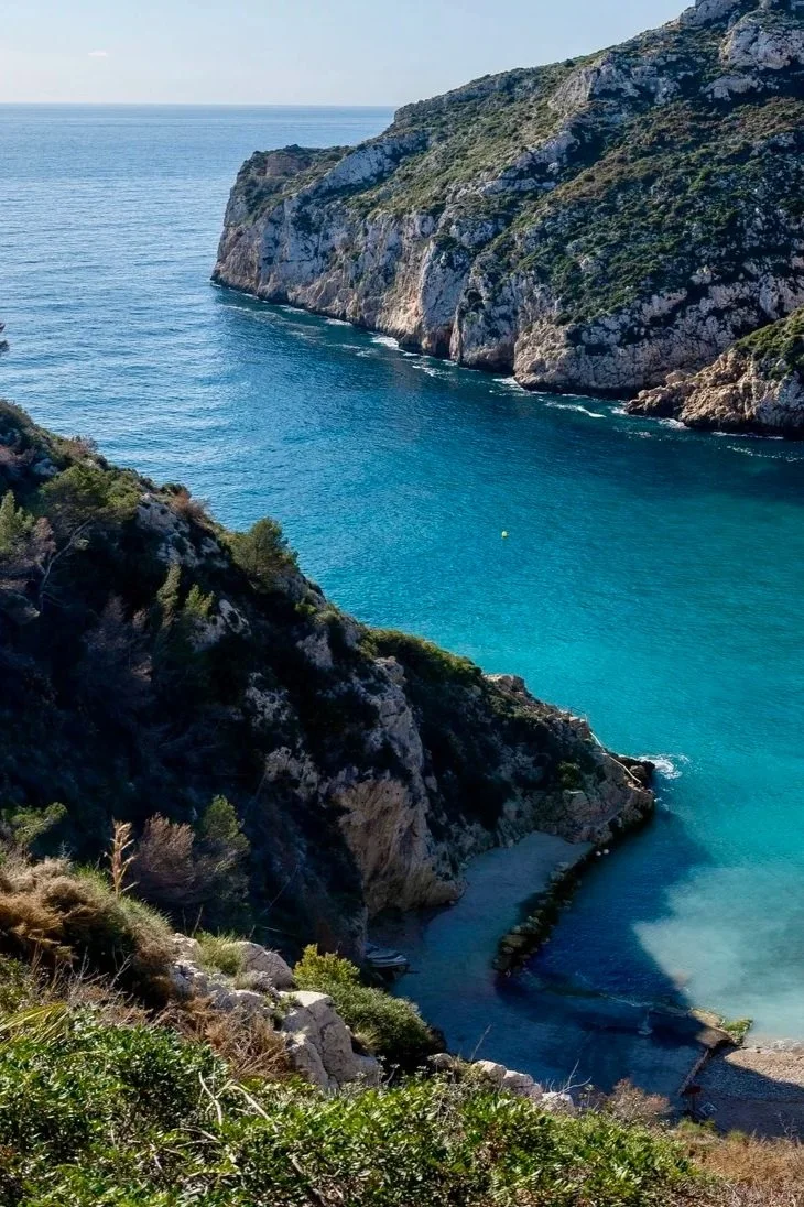 Côte rocheuse avec mer turquoise, falaises abruptes et végétation méditerranéenne.