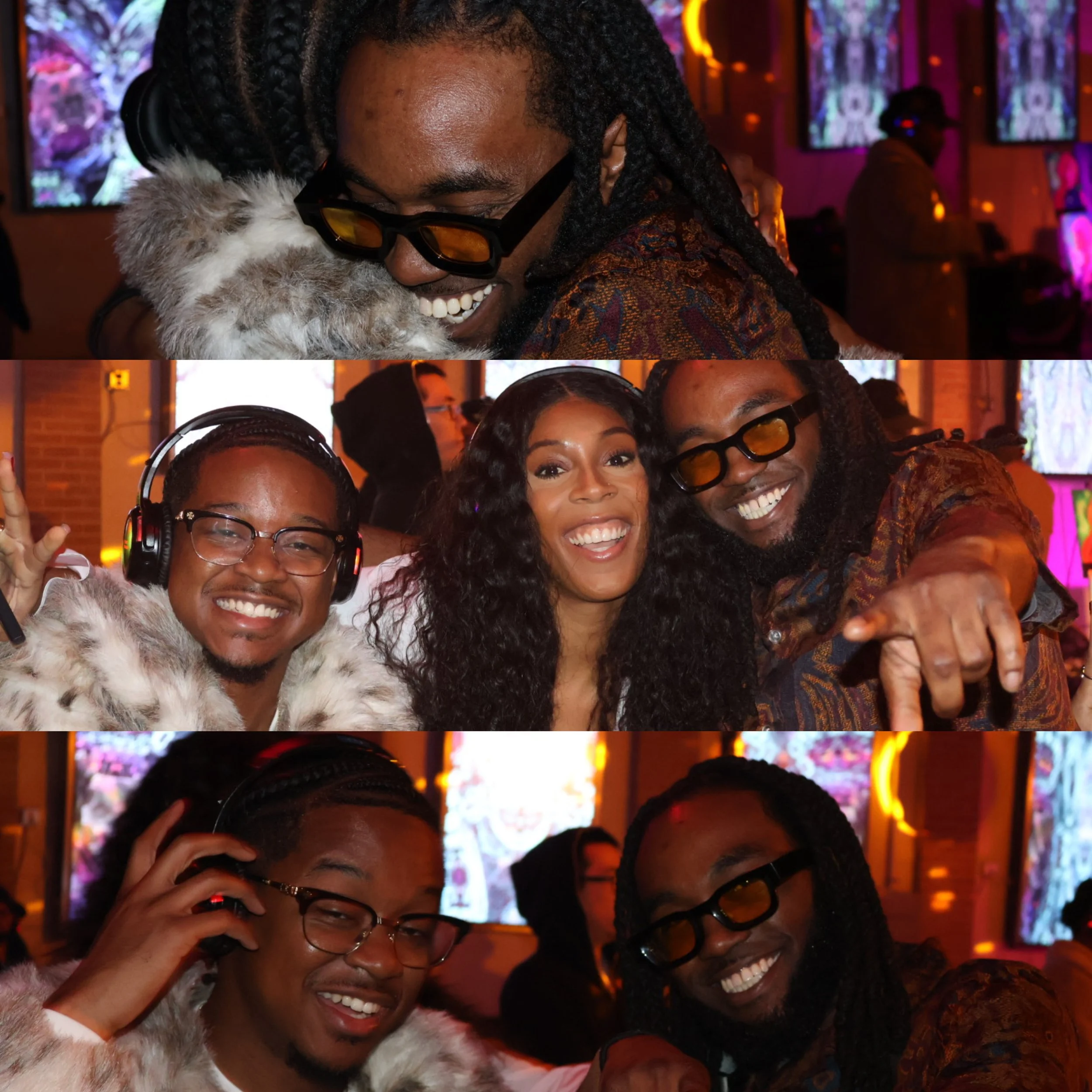 Four people smiling and taking a group selfie in a colorful, dimly lit venue with digital screens in the background. The person on the left wears headphones and glasses, the middle person has curly hair, and the right person wears glasses and has dre
