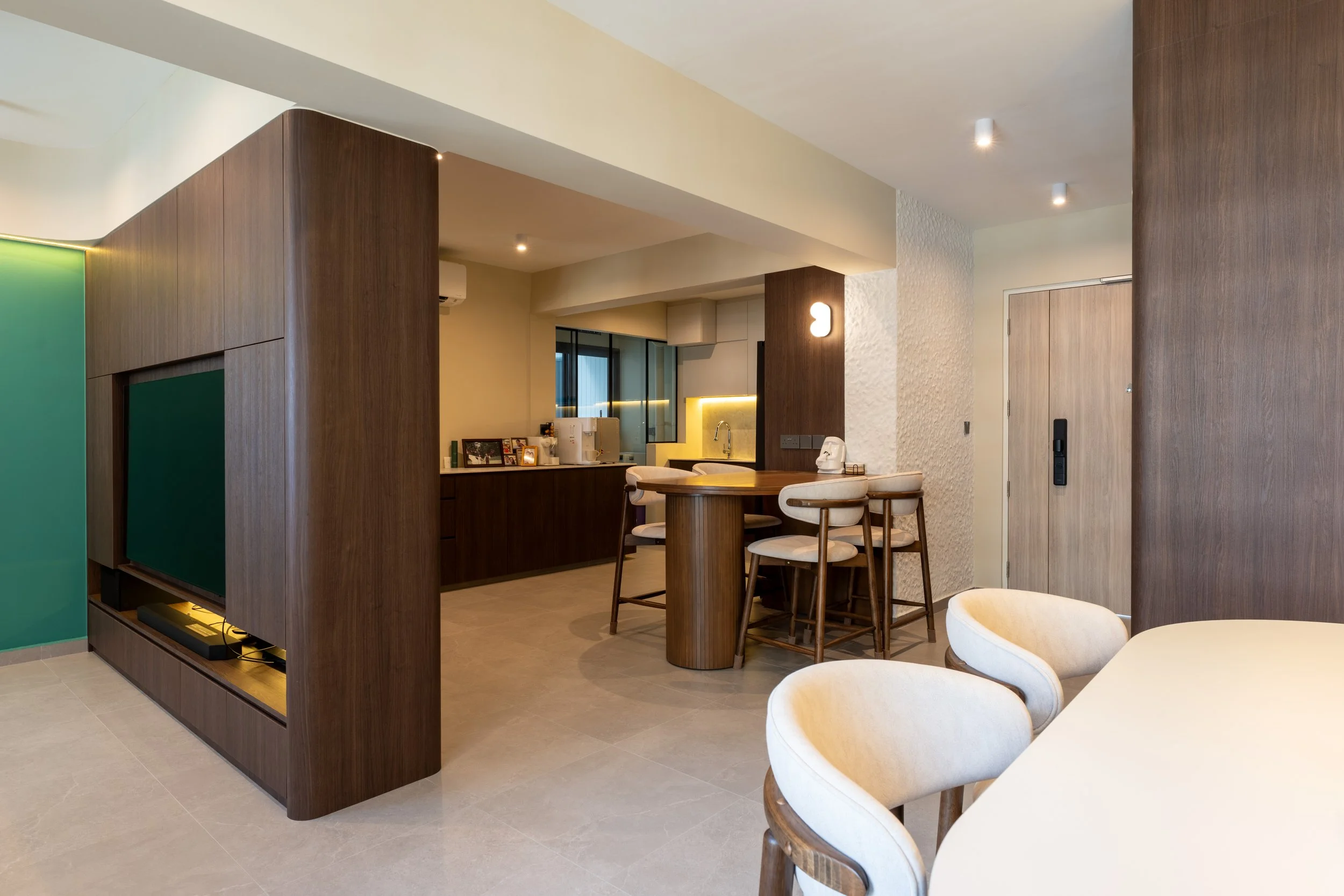 Interior view of a modern kitchen and dining area with wooden accents, beige chairs, and a white countertop.