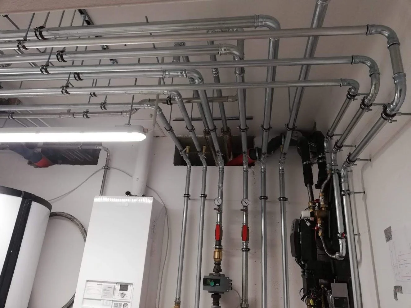 Verrohrung, Wasserleitungen und Heizungsanlage in einem Installationsraum.