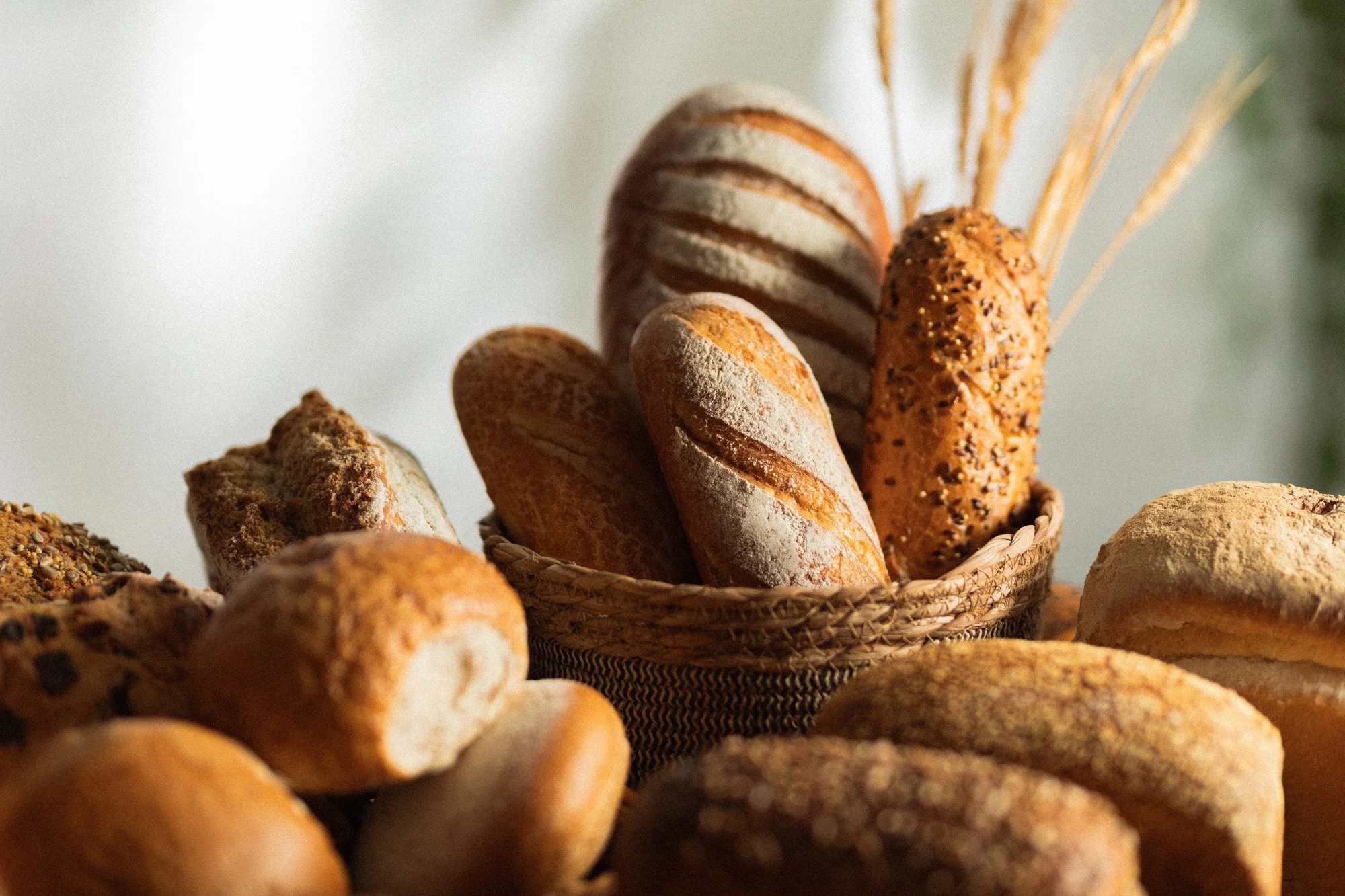 Overhead close-up of assorted baked rolls, plain and seeded, piled in wicker baskets