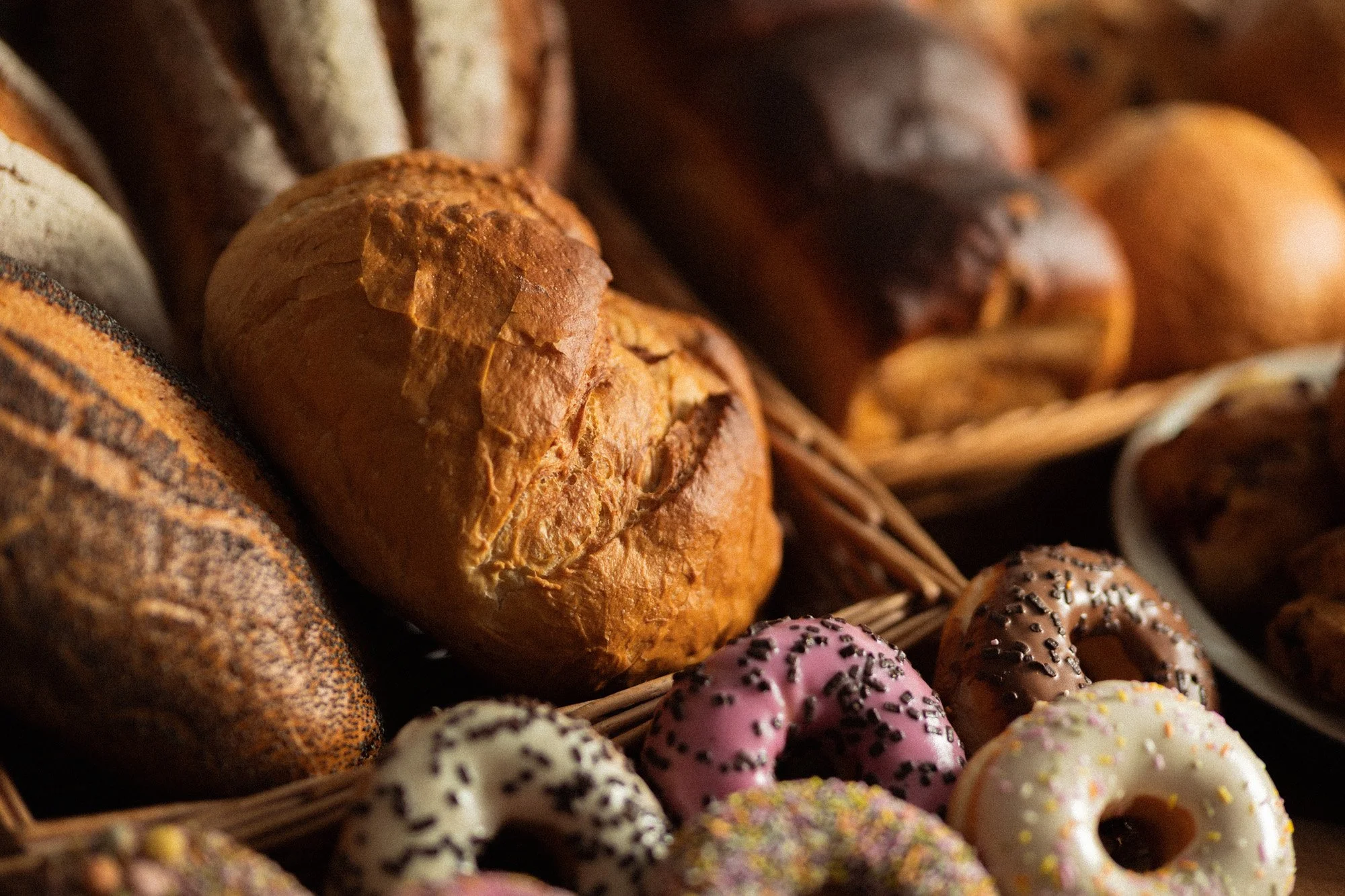 Selection of freshly baked breads, brioche rolls and iced doughnuts displayed together in baskets at O'Keeffe's Family Bakery.