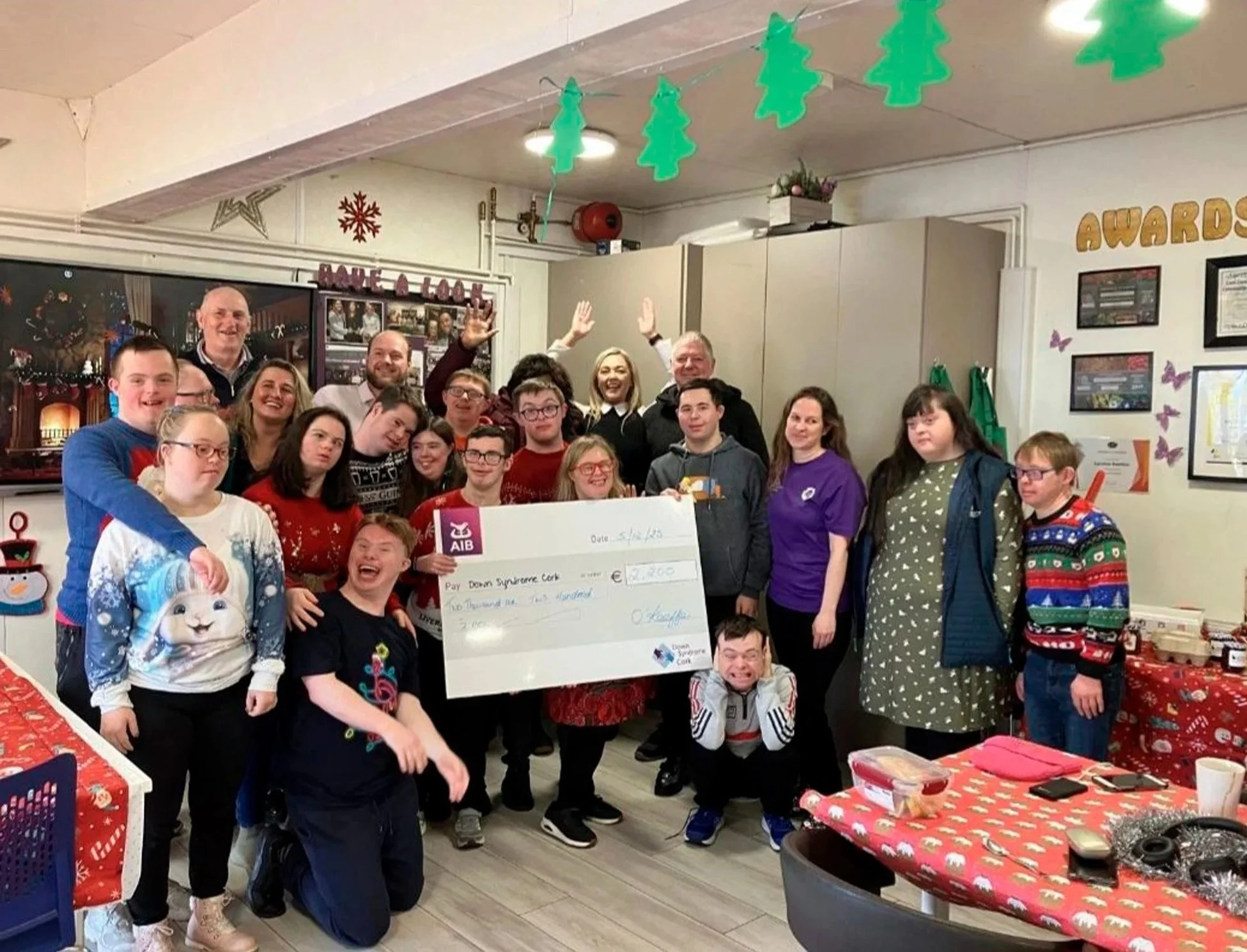 Large group photo at a Christmas party, with staff and service users holding a cheque for Down Syndrome Cork