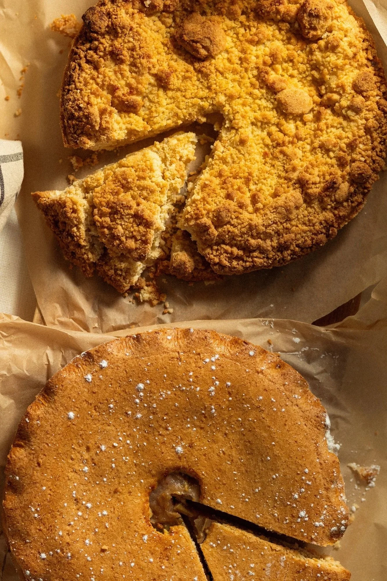 Overhead shot of two tarts side by side, one with a crumble topping, one dusted with icing sugar