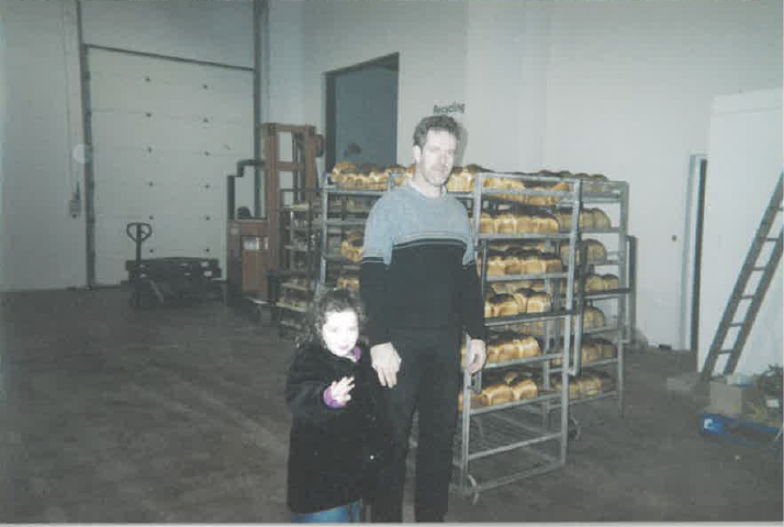 Historic photograph of a family member and child standing inside the original O'Keeffe's bakery beside racks of freshly baked bread.