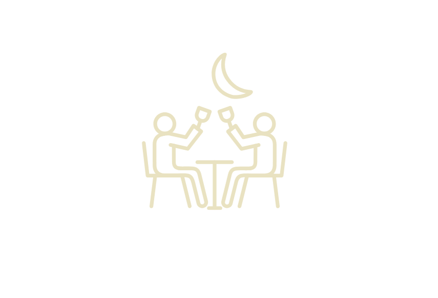 Two people sitting at a table clinking glasses under a crescent moon.