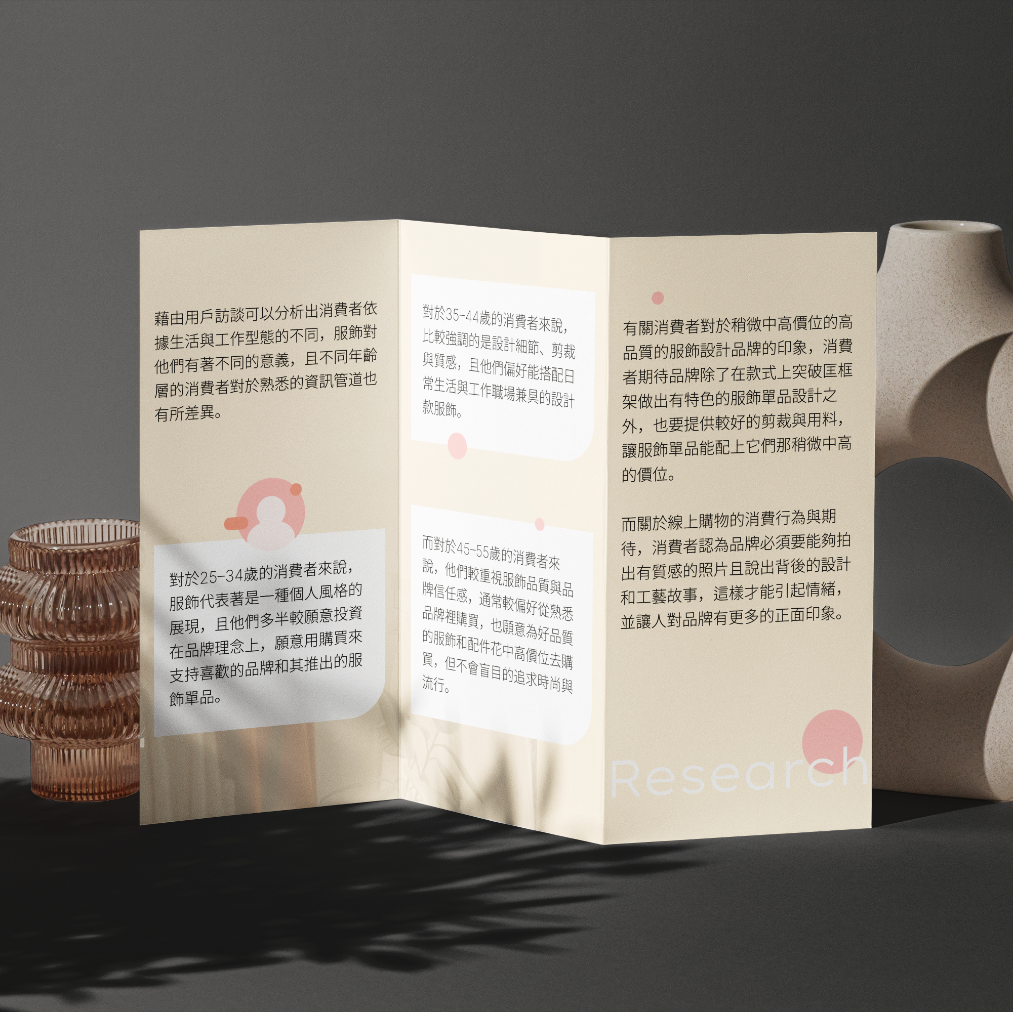 A brochure with vertically folded pages displaying text in Chinese characters and pink circular icons, placed next to a textured, beige ceramic vase on a dark surface against a gray background.