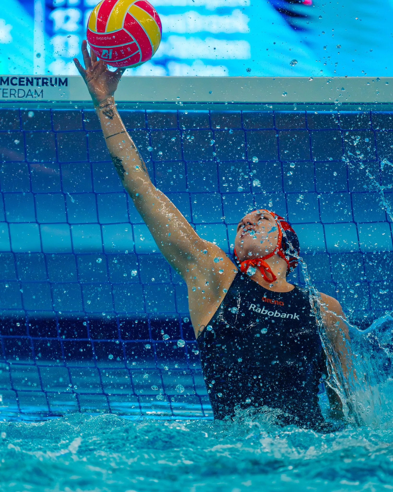 Water polo goalkeeper, Laura Aarts, blocking a shot during a match.