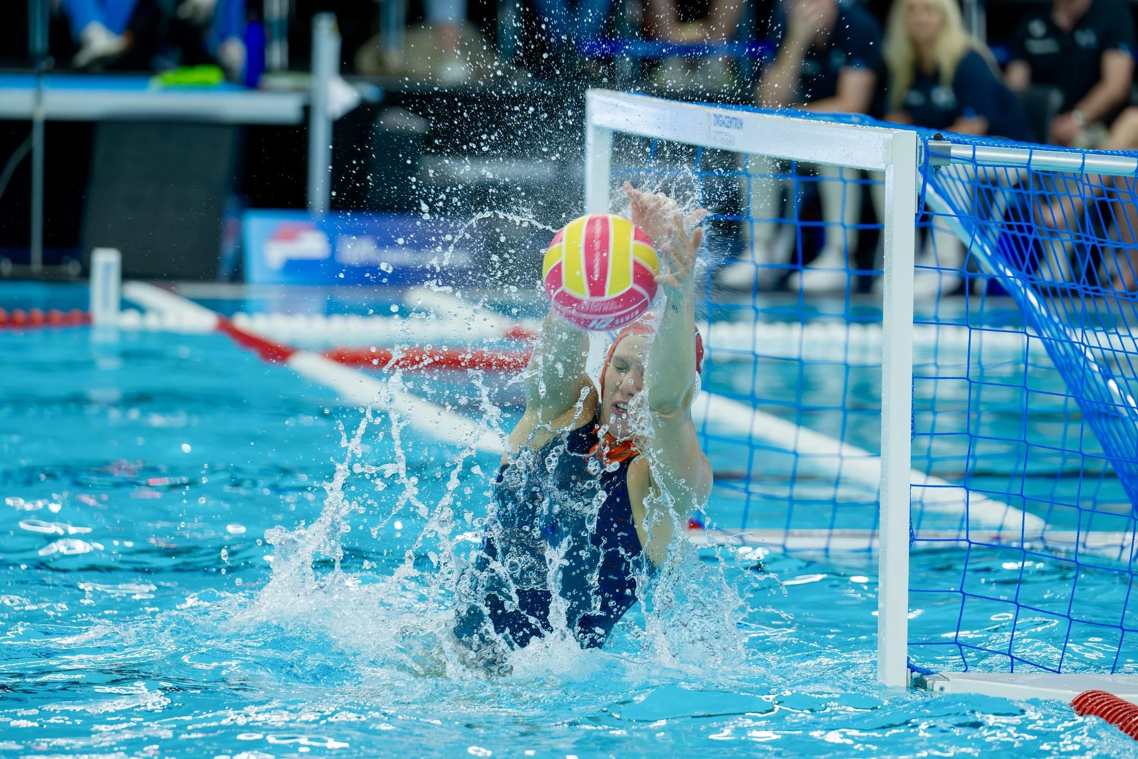 Water polo goalkeeper, Laura Aarts, blocking a shot during a match.