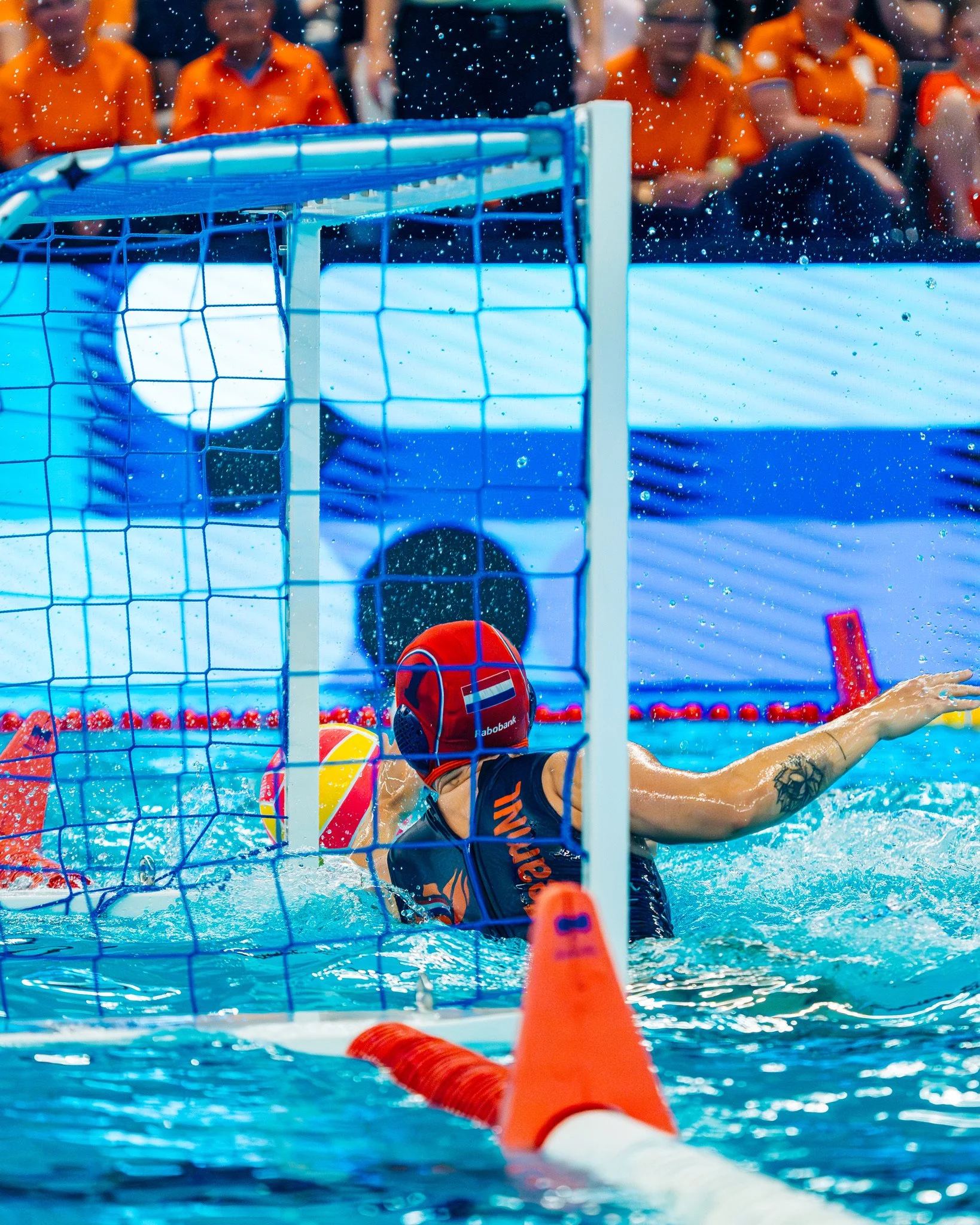 Water polo goalkeeper, Laura Aarts, blocking a shot during a match.
