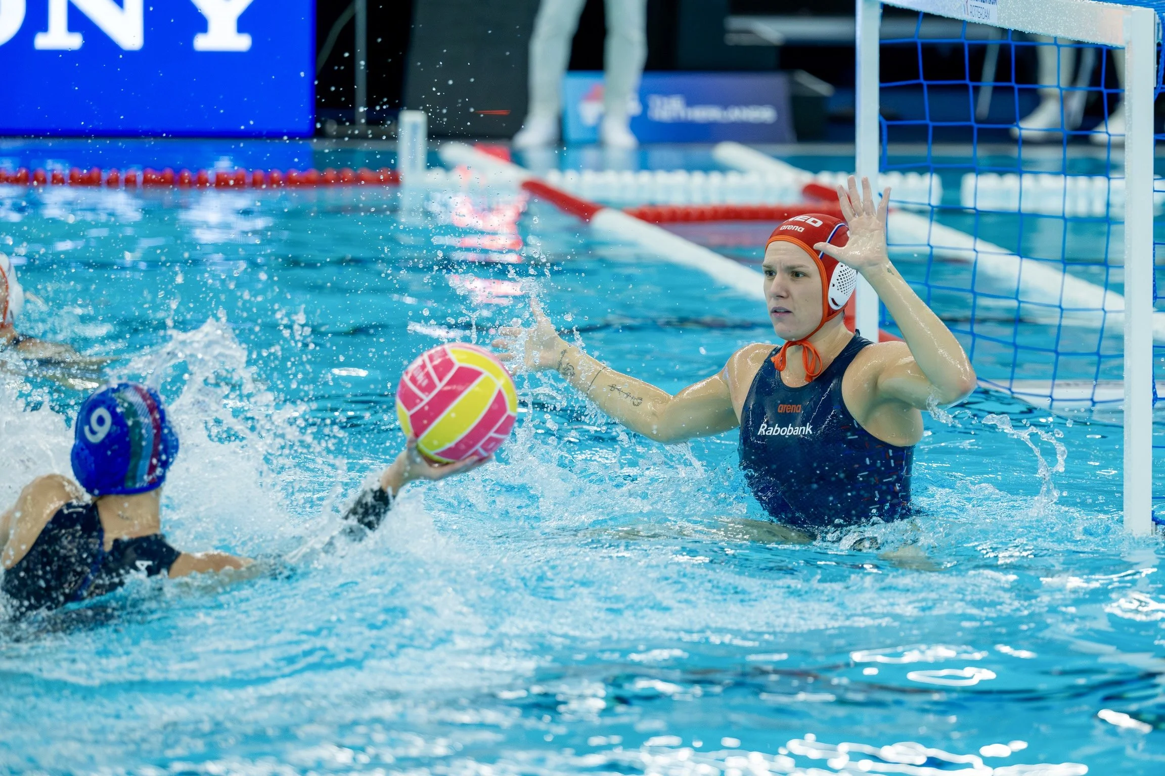 Water polo goalkeeper Laura Aarts blocking a shot during a match.