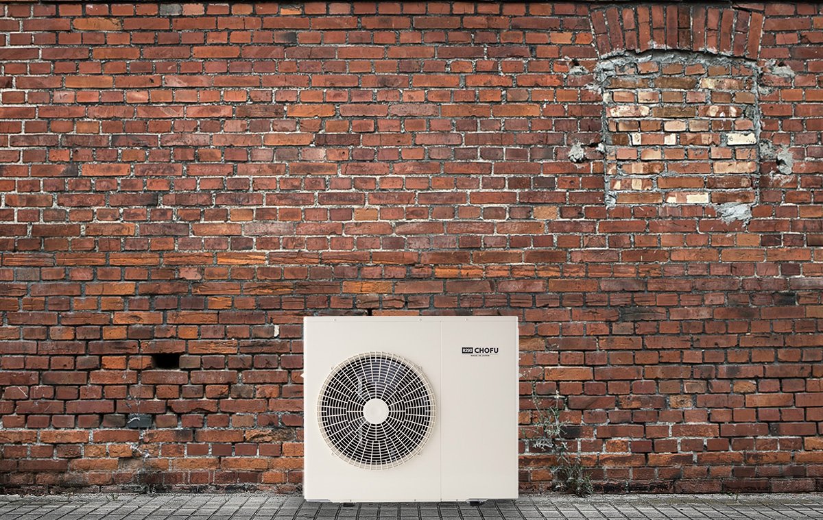 Outdoor brick wall with an air conditioning unit in front.