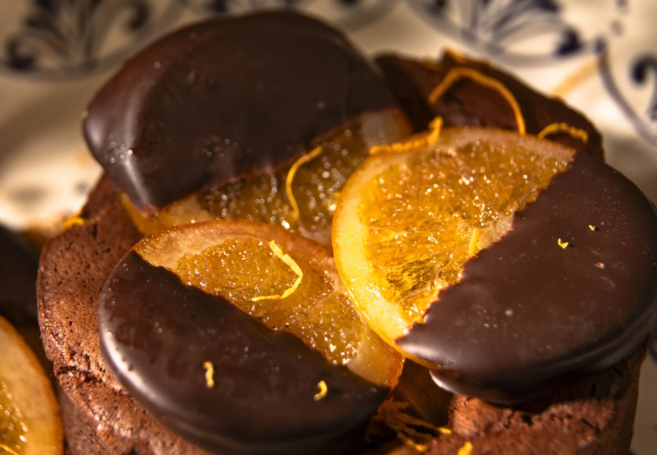 Close-up of a chocolate orange dessert topped with orange slices and thin orange zest strips.