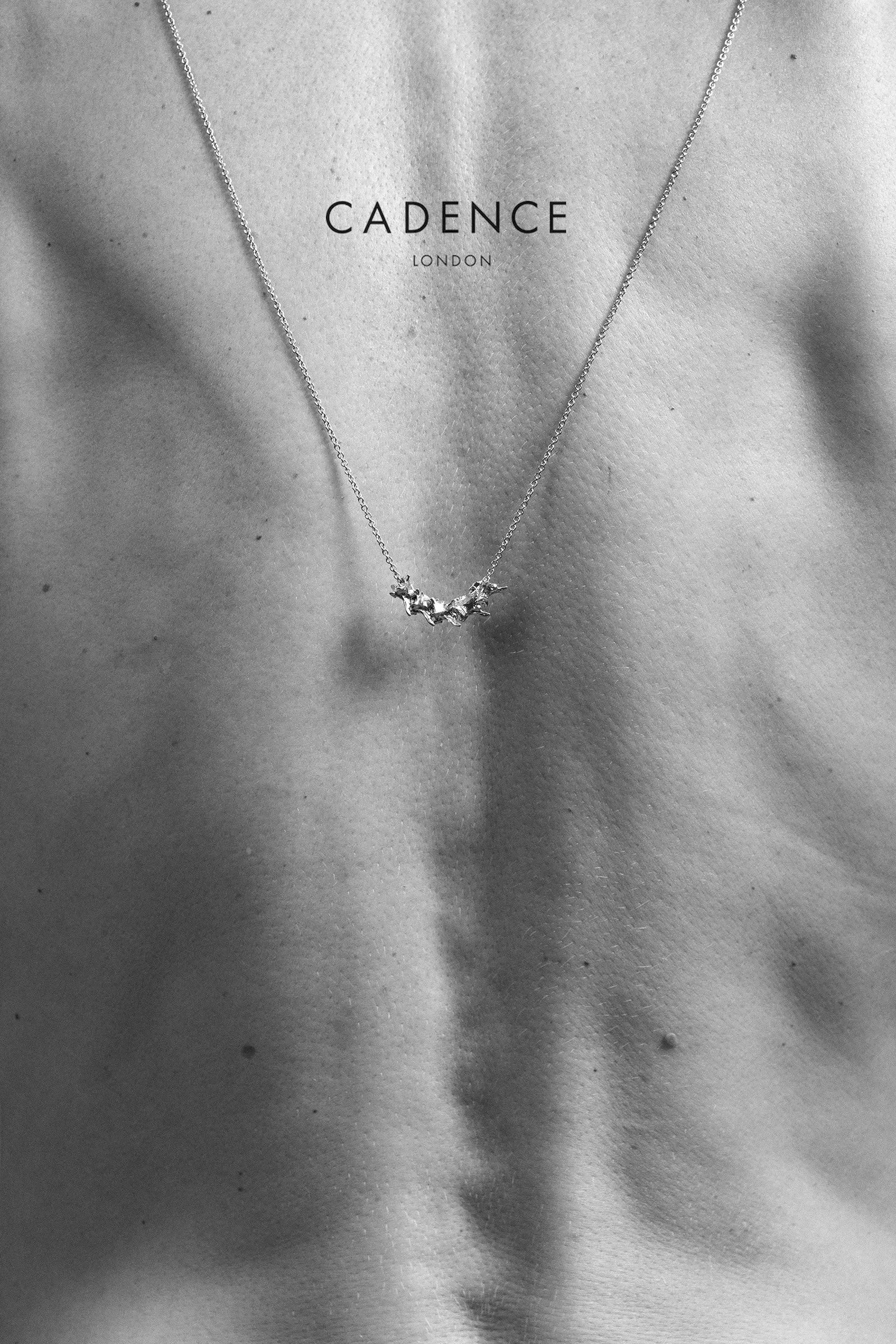 Close-up of a woman wearing a delicate necklace with a moon-shaped pendant around her neck, with the brand name 'CADENCE LONDON' written over her chest.