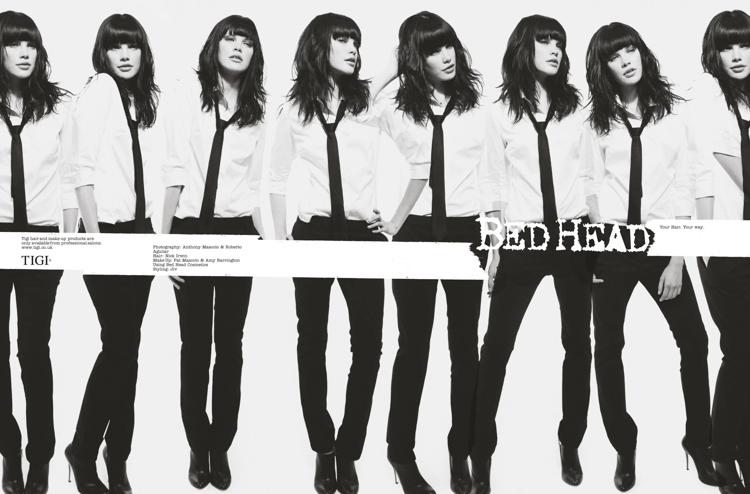 A black and white photo of multiple women with dark hair and bangs, wearing white shirts, black pants, and black ties, standing in a line. The word 'BED HEAD' is written across the bottom of the image with the tagline 'Your Hair. Your way.'