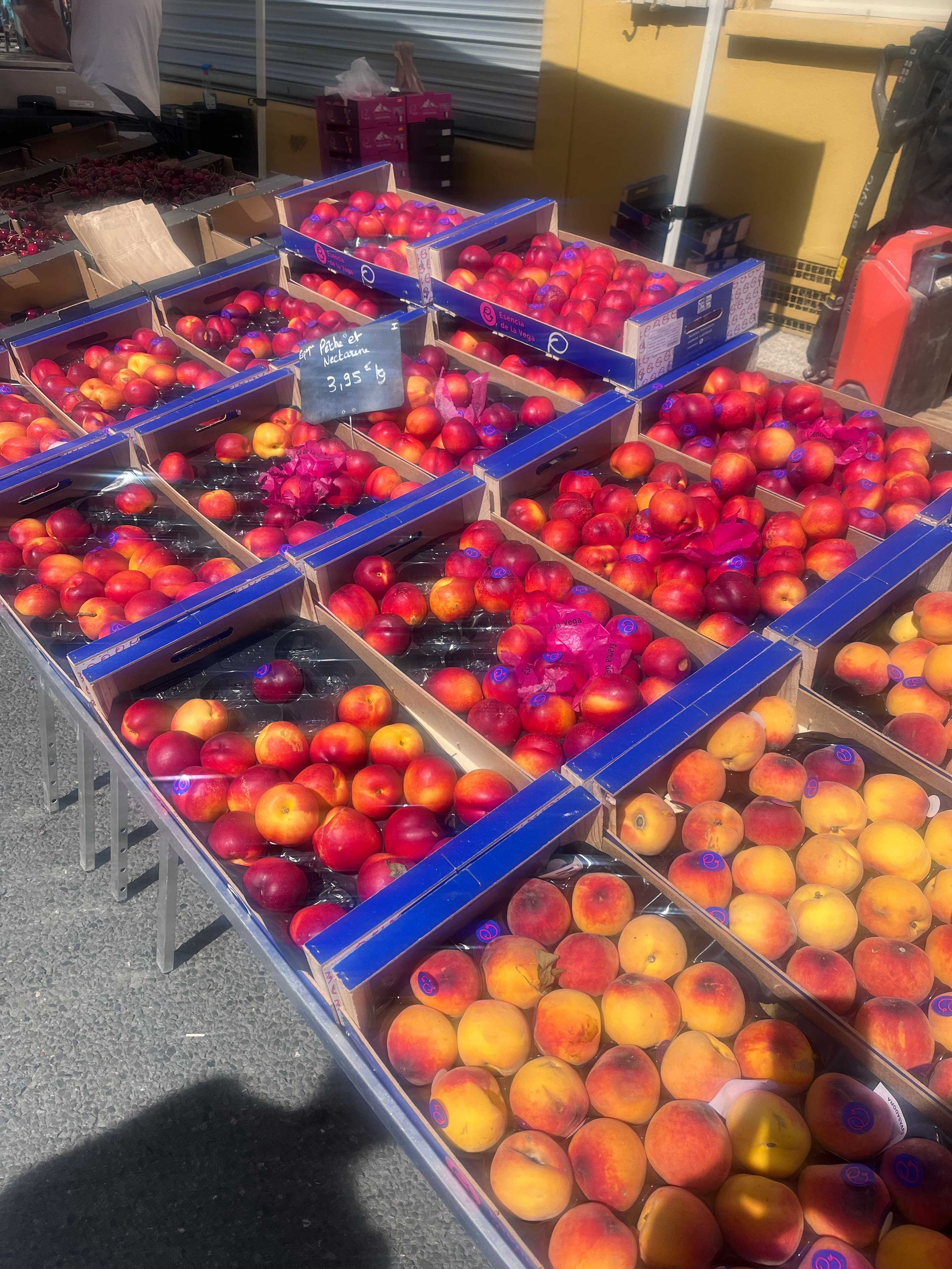 Display of several boxes of fresh peaches at an outdoor market.