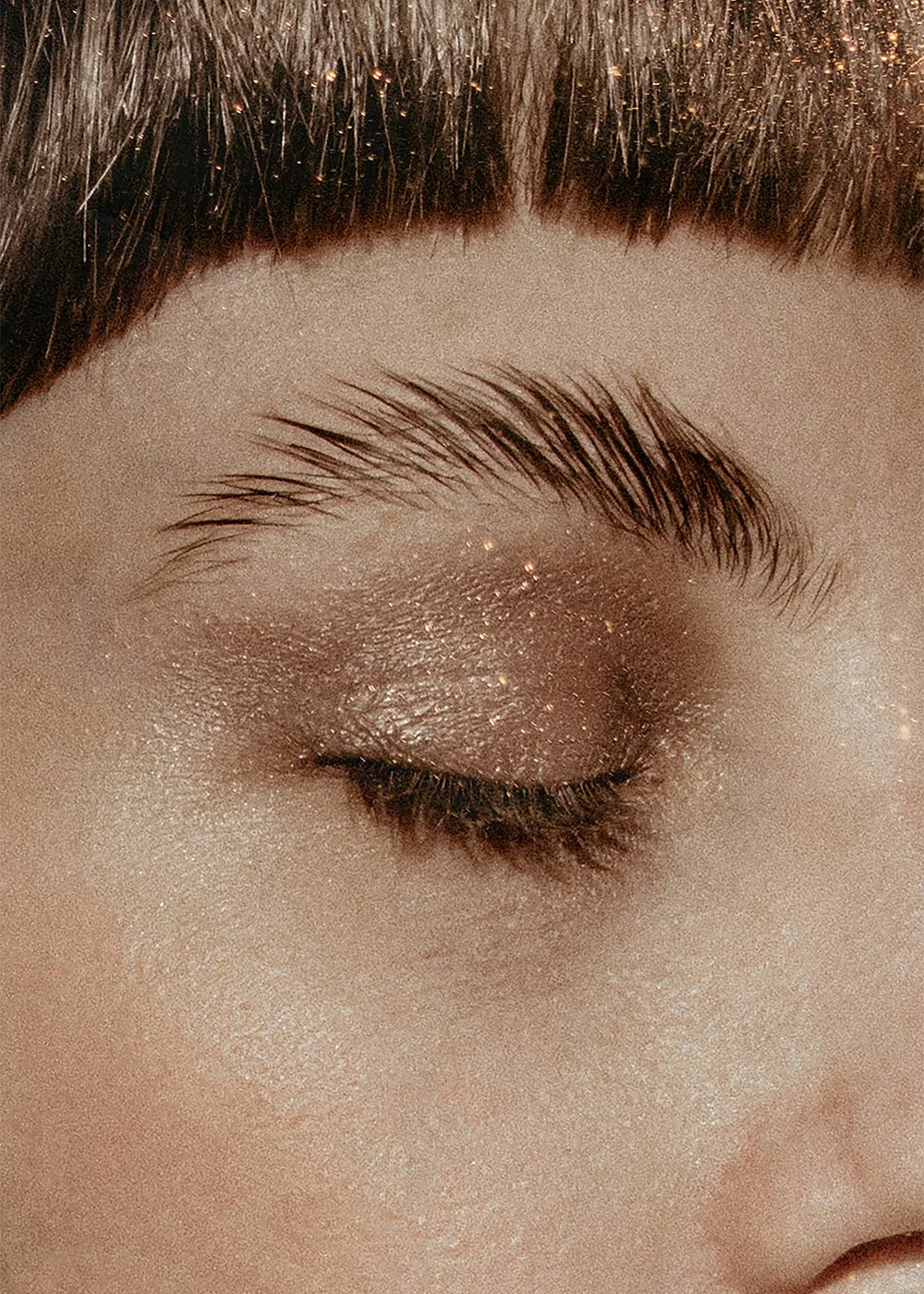 Close-up of a woman’s eyebrow and eye with shimmering makeup