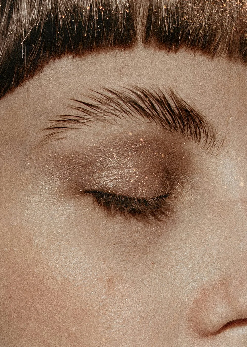 Close-up of a woman’s eyebrow and eye with shimmering makeup