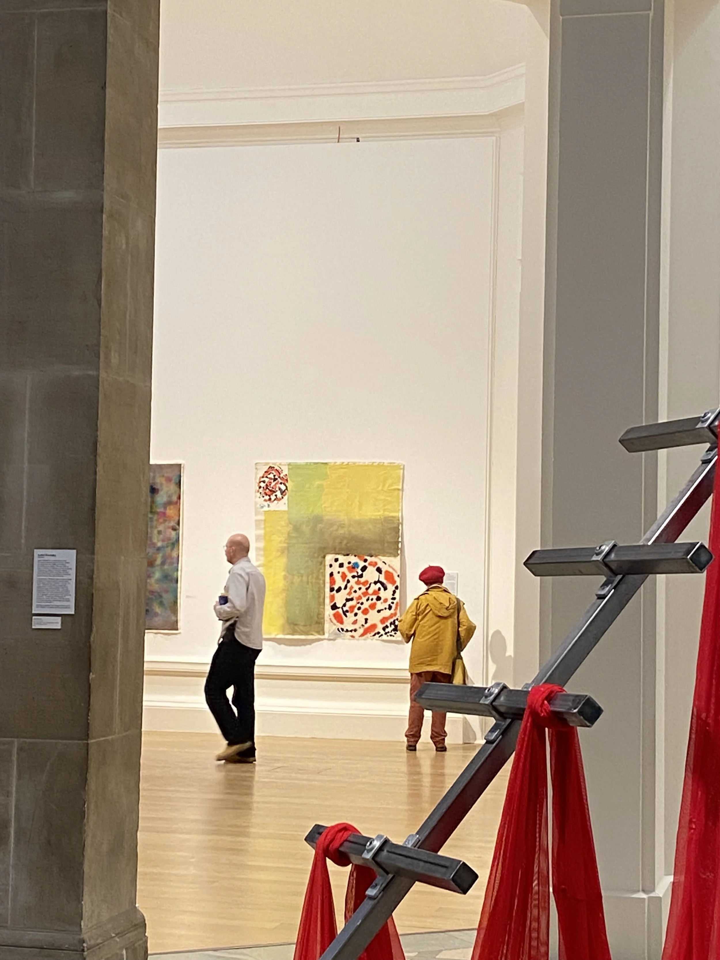 People viewing colorful abstract artwork. Installation view of Annabelle Pelaez’s 'Crimson Speckled' painting at the Royal Scottish Academy exhibition.