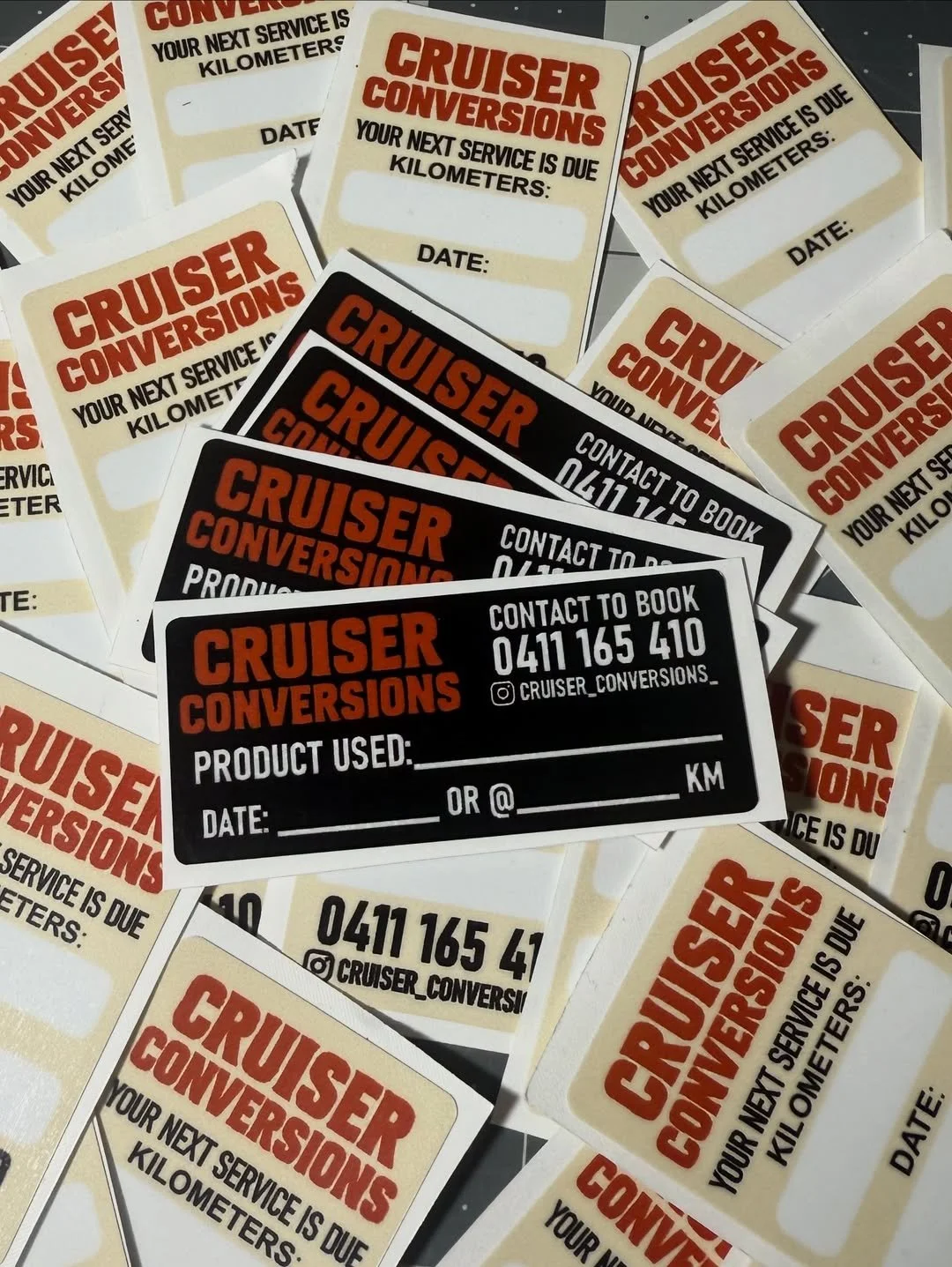 Multiple vehicle service reminder stickers for Cruiser Conversions, including black and beige designs, with contact information and spaces for service details and date.