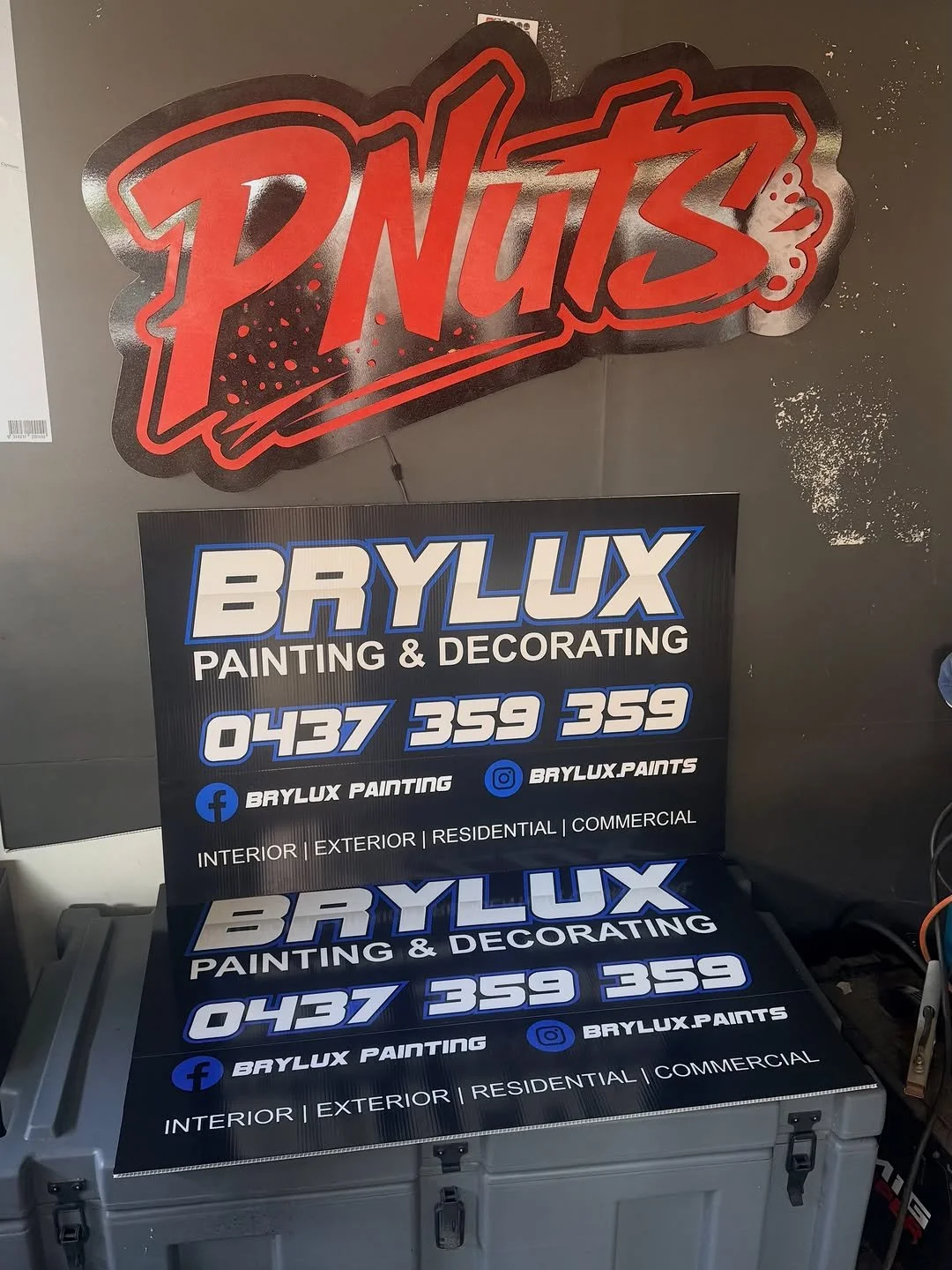 Sign displaying the name Bry Lux Painting & Decorating with contact number 0437 359 359, social media handles, and services in interior, exterior, residential, and commercial painting.
