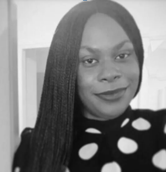 A woman with long, straight hair wearing a polka dot top and smiling in a black-and-white photo.