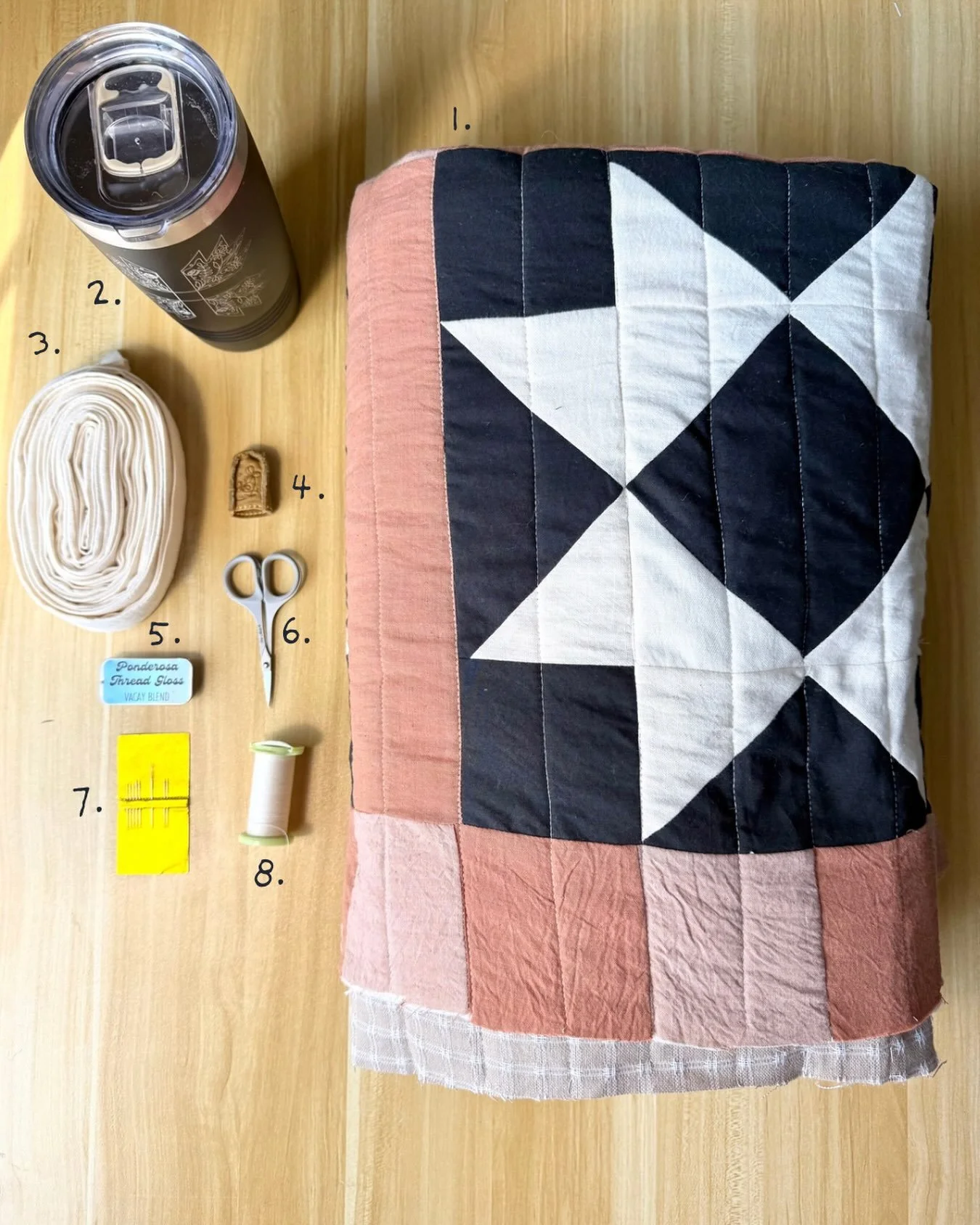 Hand binding supplies 🪡

1.Quilted juniper quilt 
2. Maple latte in my favorite cup by @amandalynnmade 
3. Binding roll 
4. @cloverusa leather thimble 
5. Beeswax thread gloss 
6. Thread snips 
7. Handbinding sharps 
8. Hand quilting thread 

#heirl