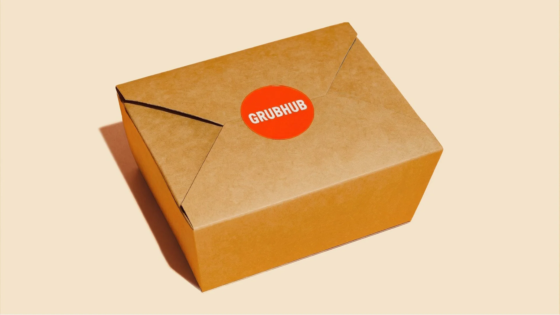 A brown cardboard box with a red circular sticker labeled 'GRUBHUB' in white text on the top.
