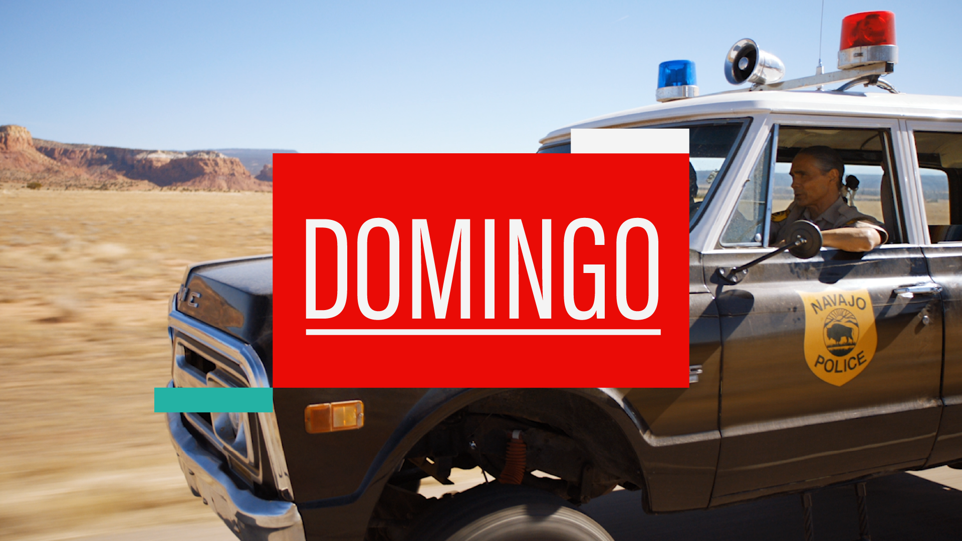 A police vehicle with a 'Navajo Police' badge is driving through a desert landscape with mesas in the background, and a large red overlay with the word 'DOMINGO' in white text.