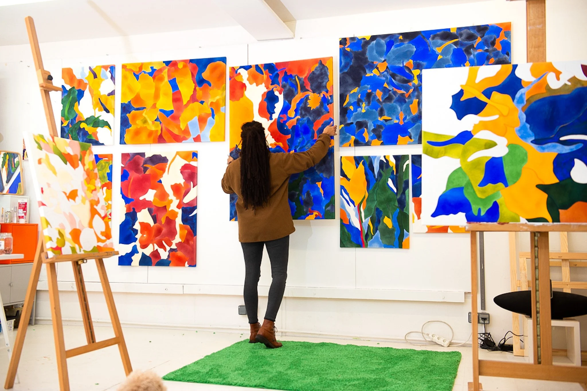 UNE FEMME QUI DESSINE DES PEINTURES ABSTRAITES COLORÉES SUR UN MUR BLANC DANS UNE GALERIE D'ART.