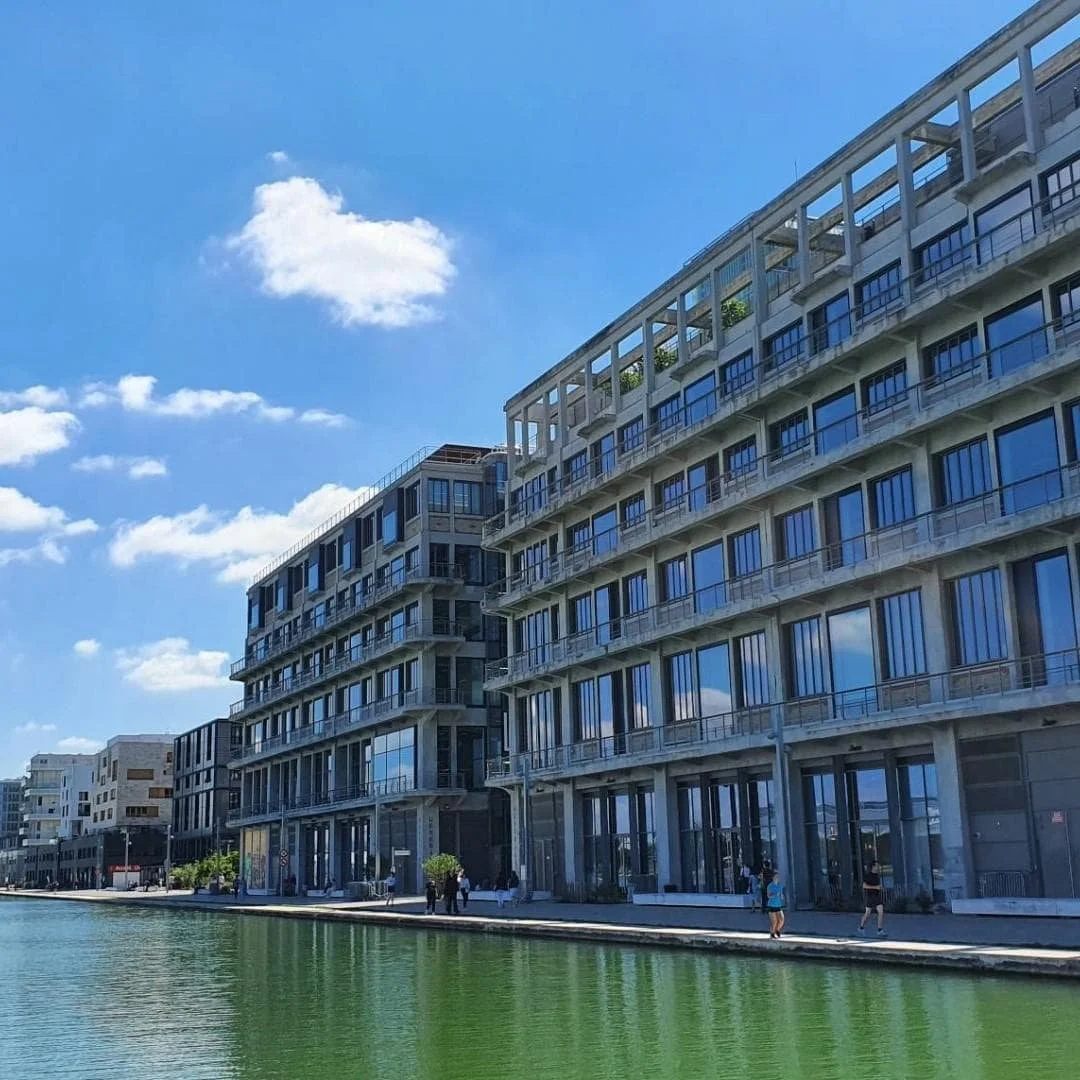 Bâtiments modernes le long d'un canal avec un ciel bleu et quelques nuages