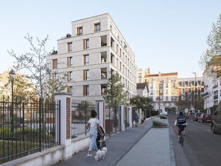 Une rue urbaine avec des immeubles modernes, des piétons dont une femme avec un chien et un cycliste, le tout sous un ciel clair.