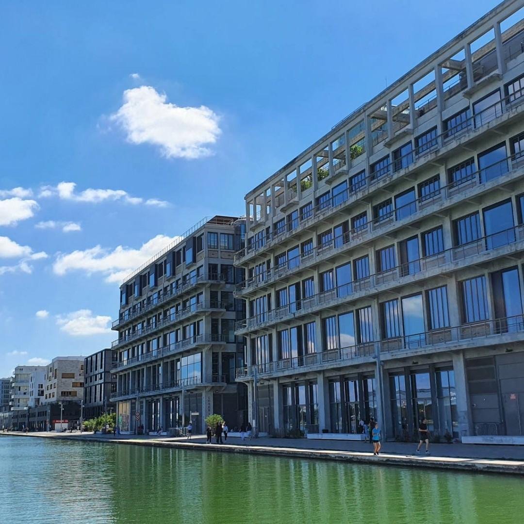 Bâtiments modernes le long d'un canal avec un ciel bleu et quelques nuages