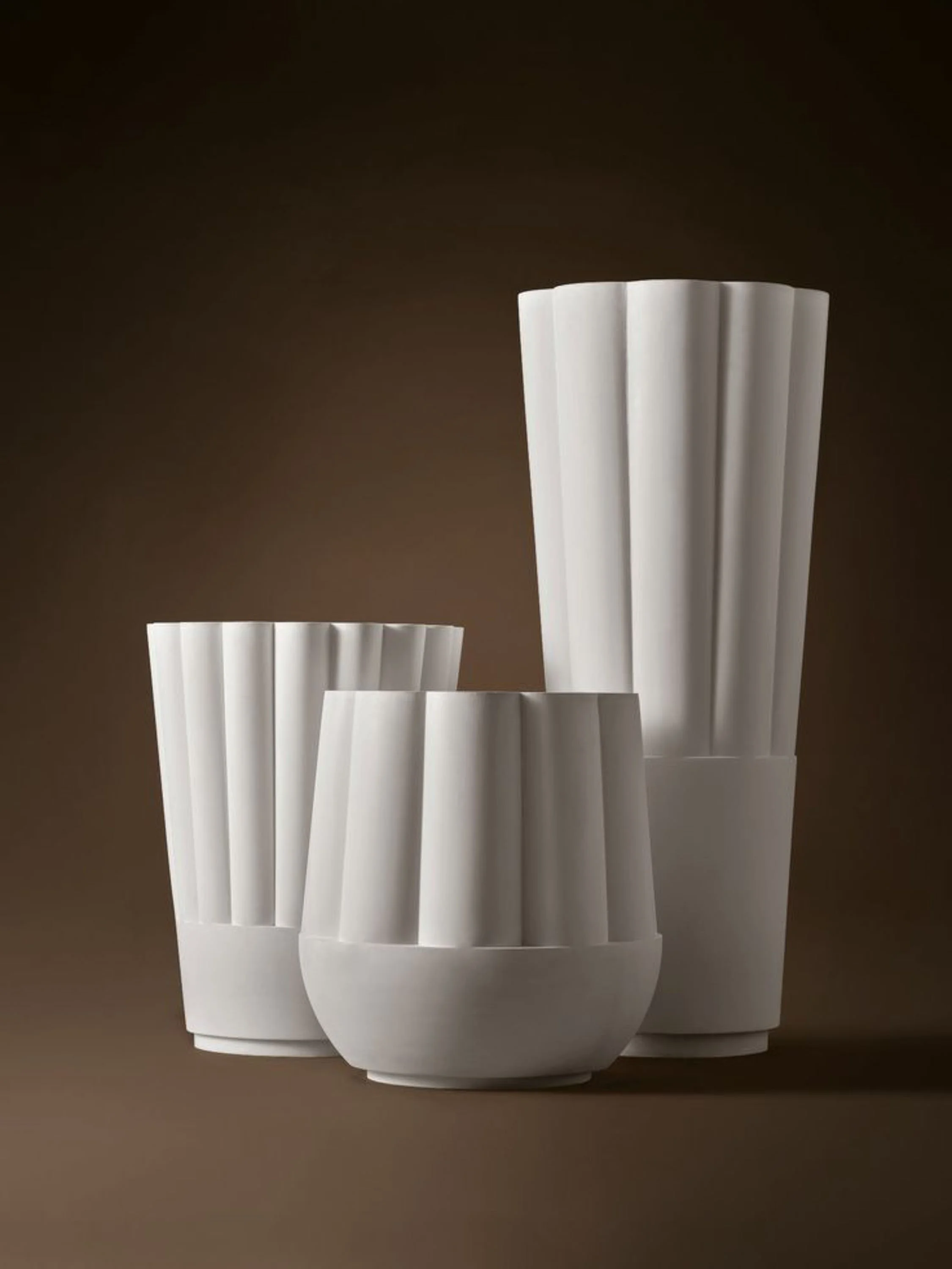 A collection of white paper cups with vertical ridges, arranged in a group against a dark background.