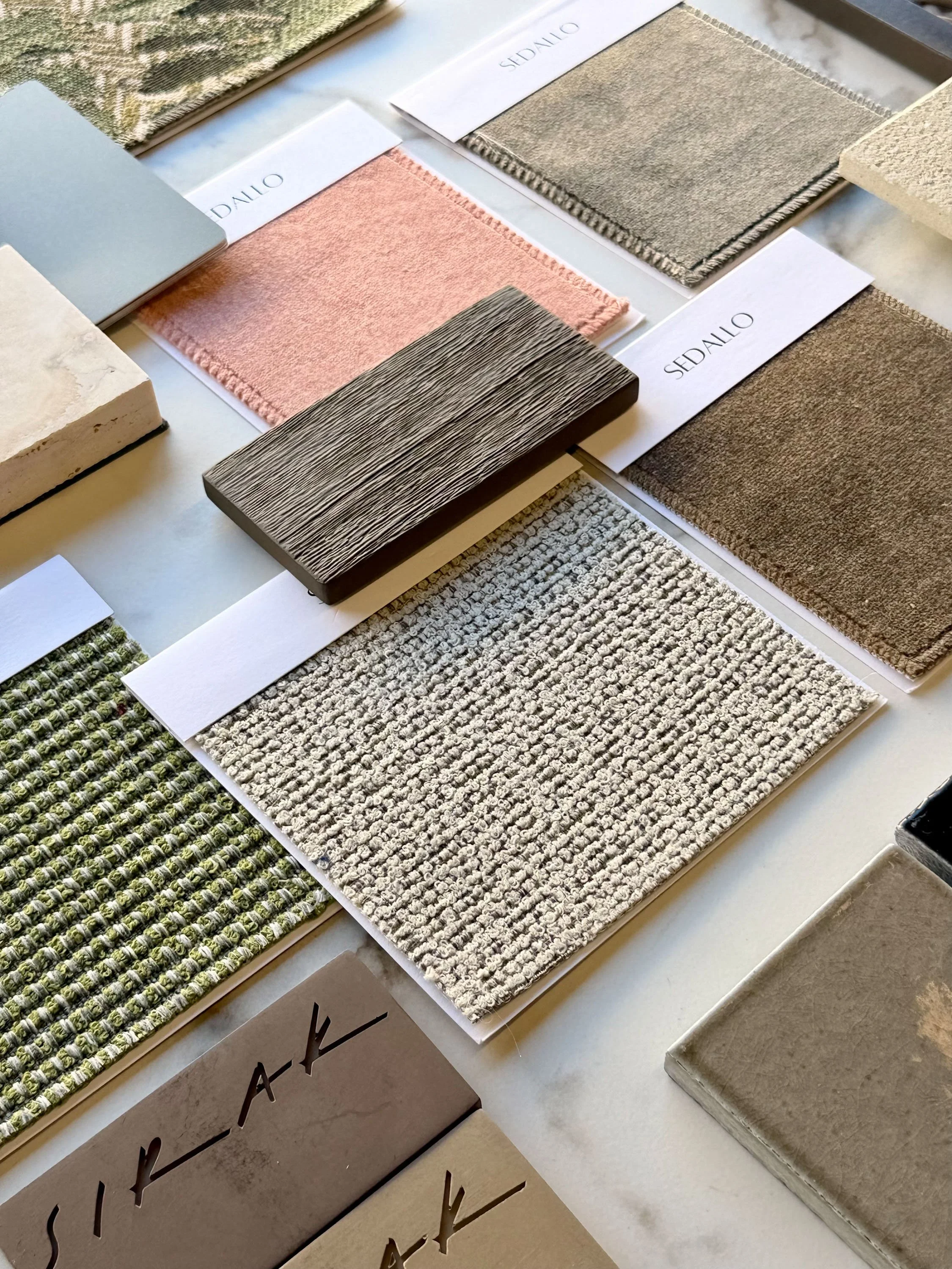 Samples of various interior fabric and carpet swatches in different colors, textures, and patterns displayed on a table.
