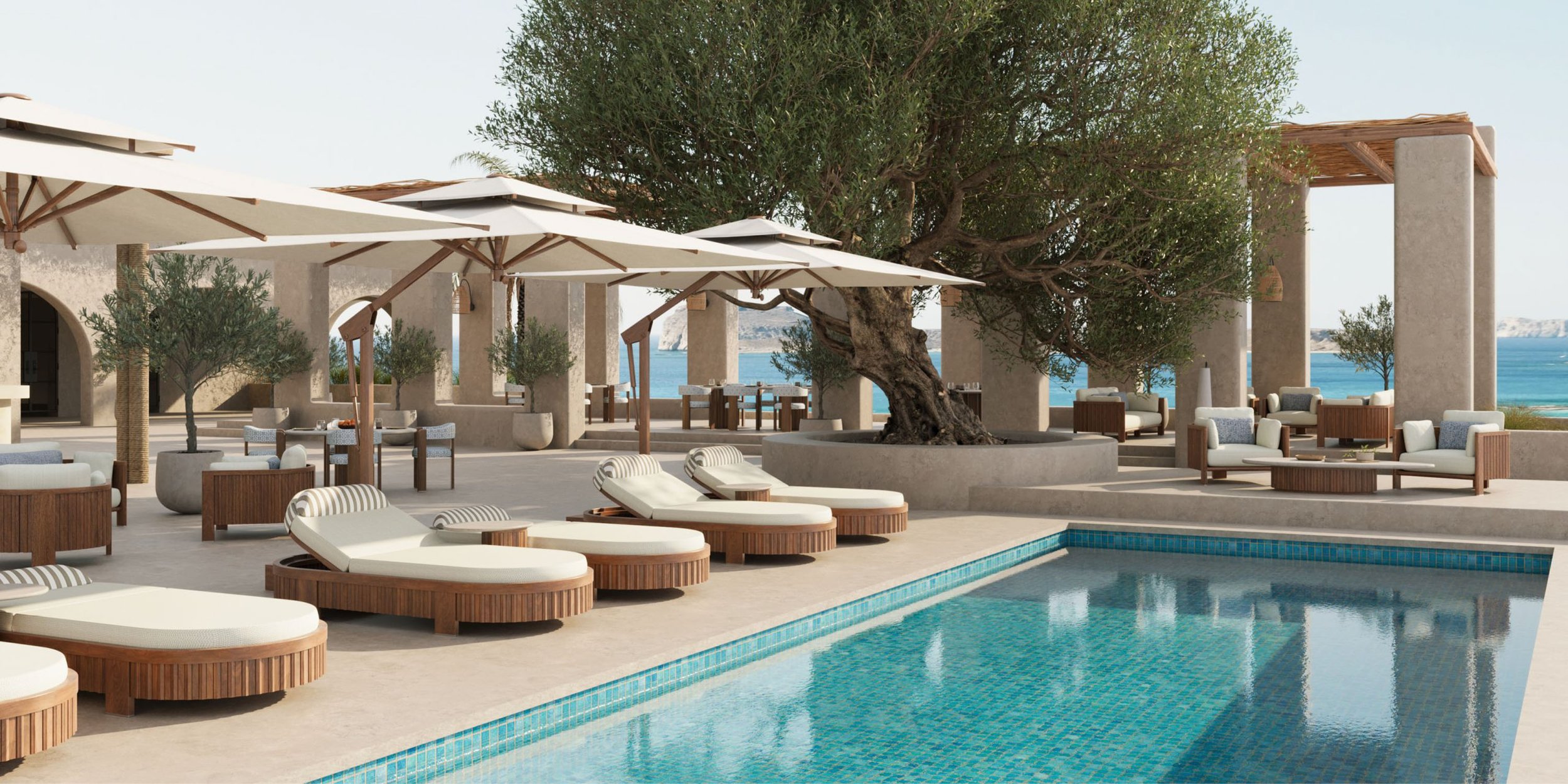 Luxury outdoor pool area with white loungers, umbrellas, and seating, featuring a large tree in the center, overlooking the ocean in the background.
