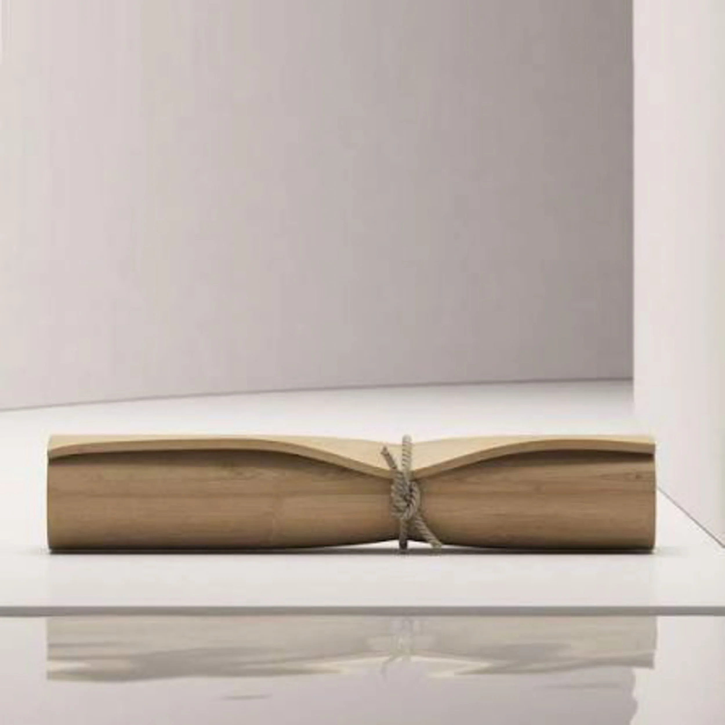 A small closed book with a beige cover and blank pages, placed on a light-colored surface near what looks like roller shades or blinds.