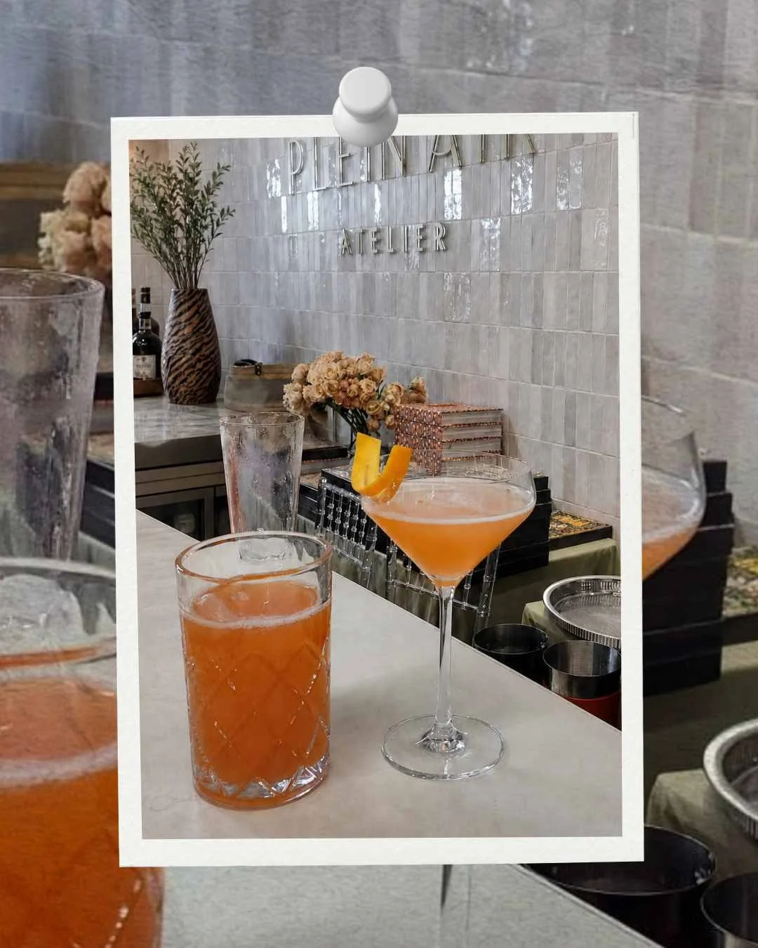 Close-up of a clipboard or photo frame with a picture of cocktails on a bar or table, with blurred interior decor in the background.