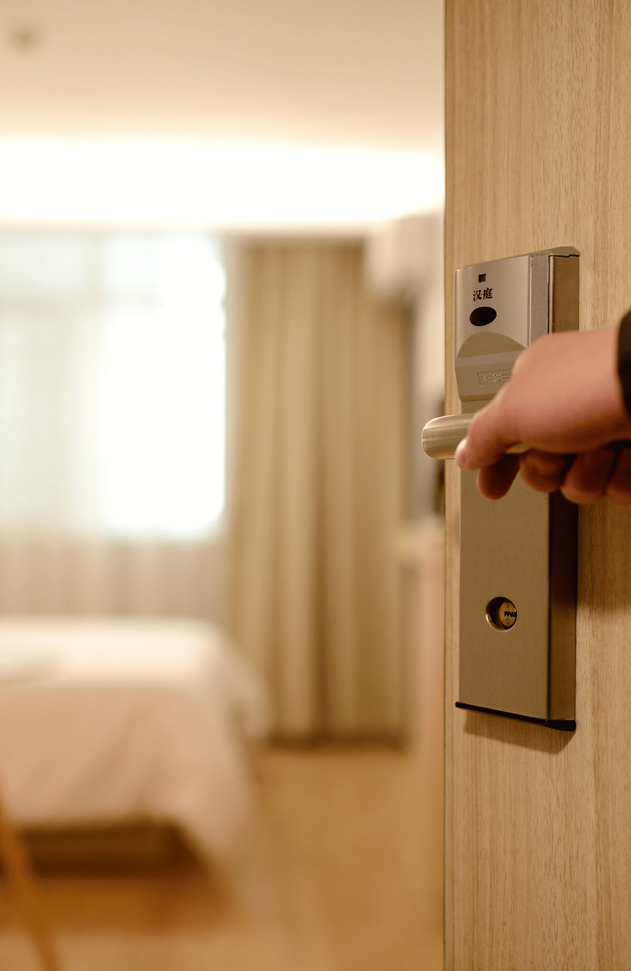 Opening the door to a hotel room with a bed inside with white linens
