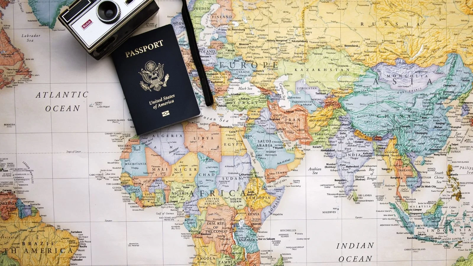 A map and a camera and a passport on a desk showing how to choose the right vacation destination