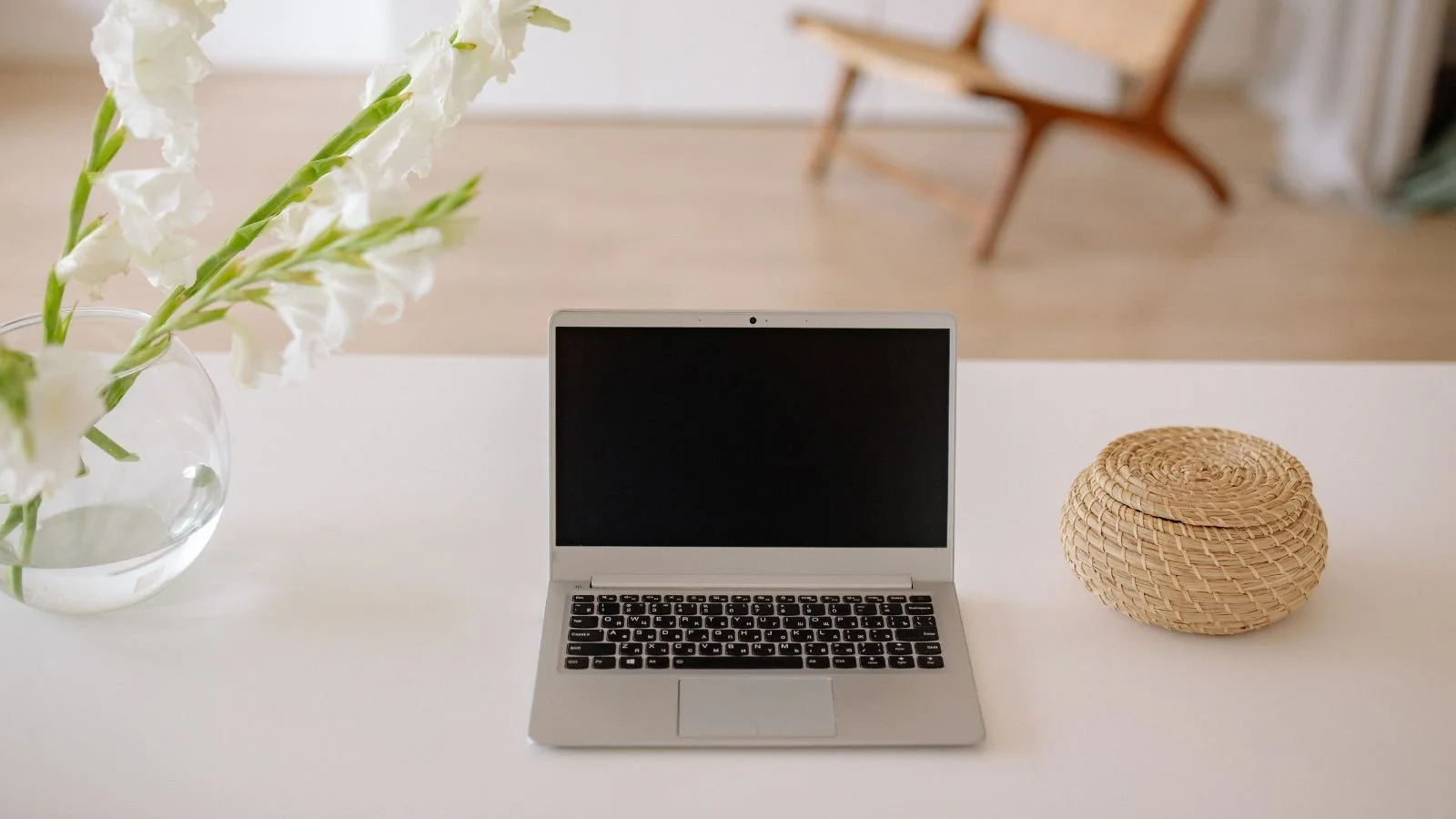 A laptop on a desk with flowers ready to plan a future vacation.