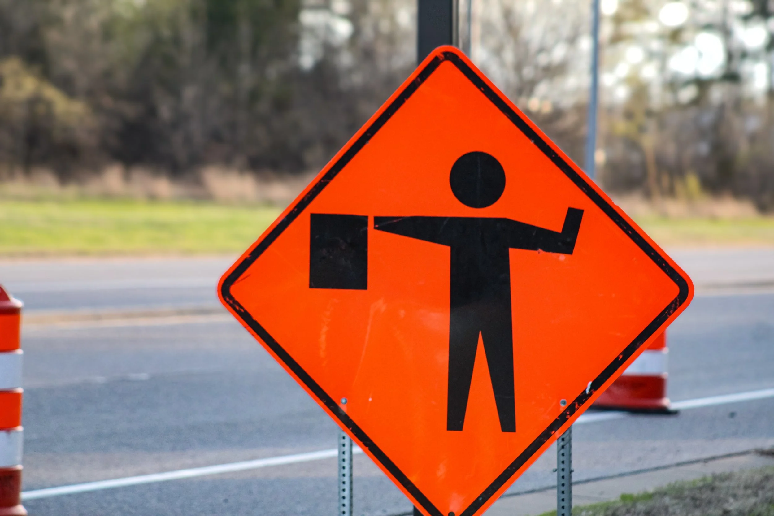 Traffic construction sign warning of roadwork ahead with a person and a shovel icon, placed on a roadside.